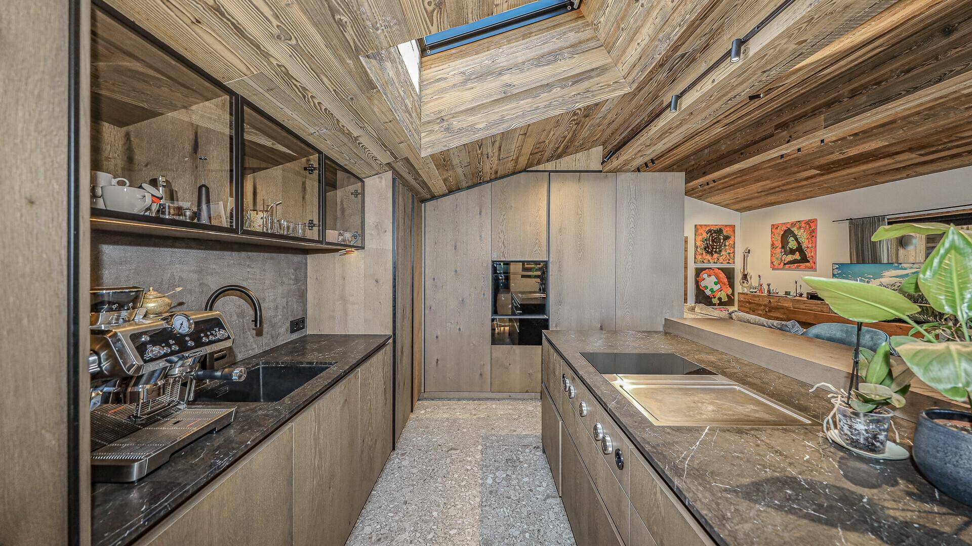 Hochwertige Küche mit dunklen Arbeitsplatten, integrierten Geräten und Holzelementen.