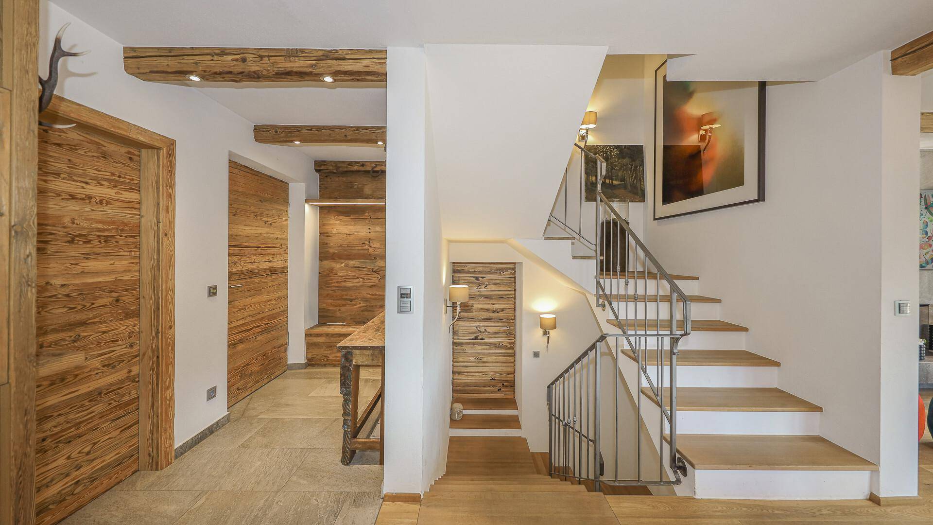 Heller Eingangsbereich mit Holzvertäfelung, Treppe und alpinen Dekorationselementen.