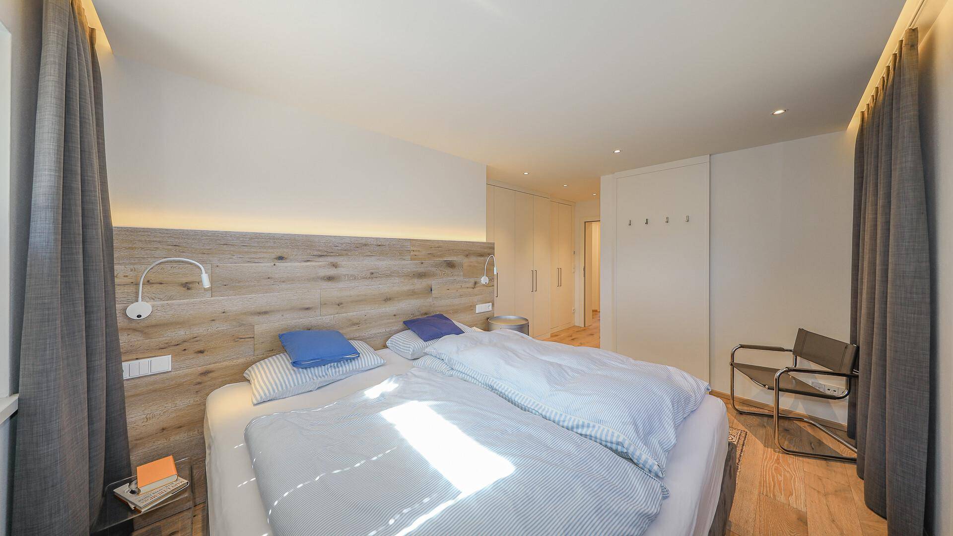 Helles Schlafzimmer mit Holzakzenten, Doppelbett und integrierten Schränken.