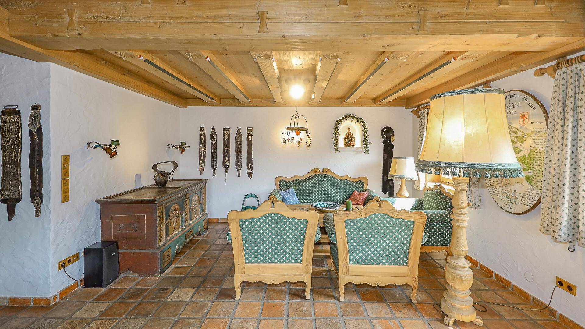 Rustikales Wohnzimmer mit Holzbalkendecke, traditionellen Möbeln und dekorativen Elementen.