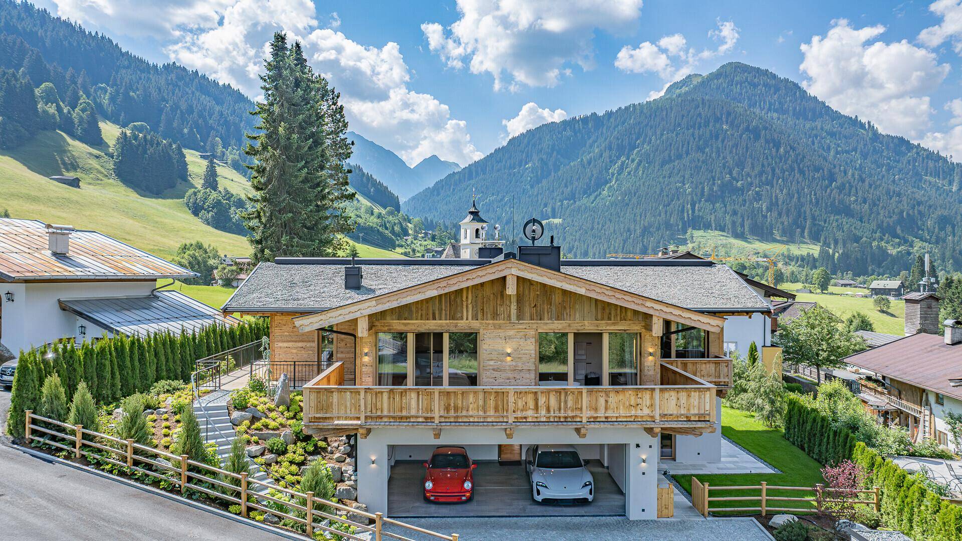 Elegantes Chalet mit traditioneller Holzfassade, integrierter Garage und Bergblick in alpiner Umgebung.