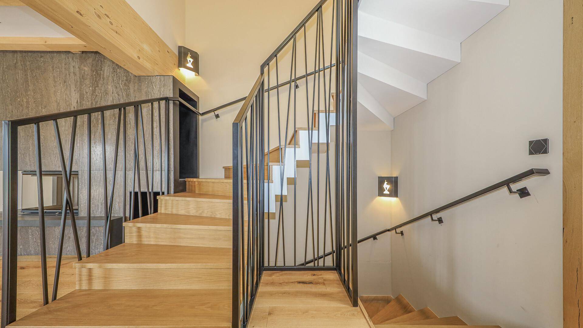 Elegante Holztreppe mit modernem Metallgeländer und indirekter Beleuchtung.