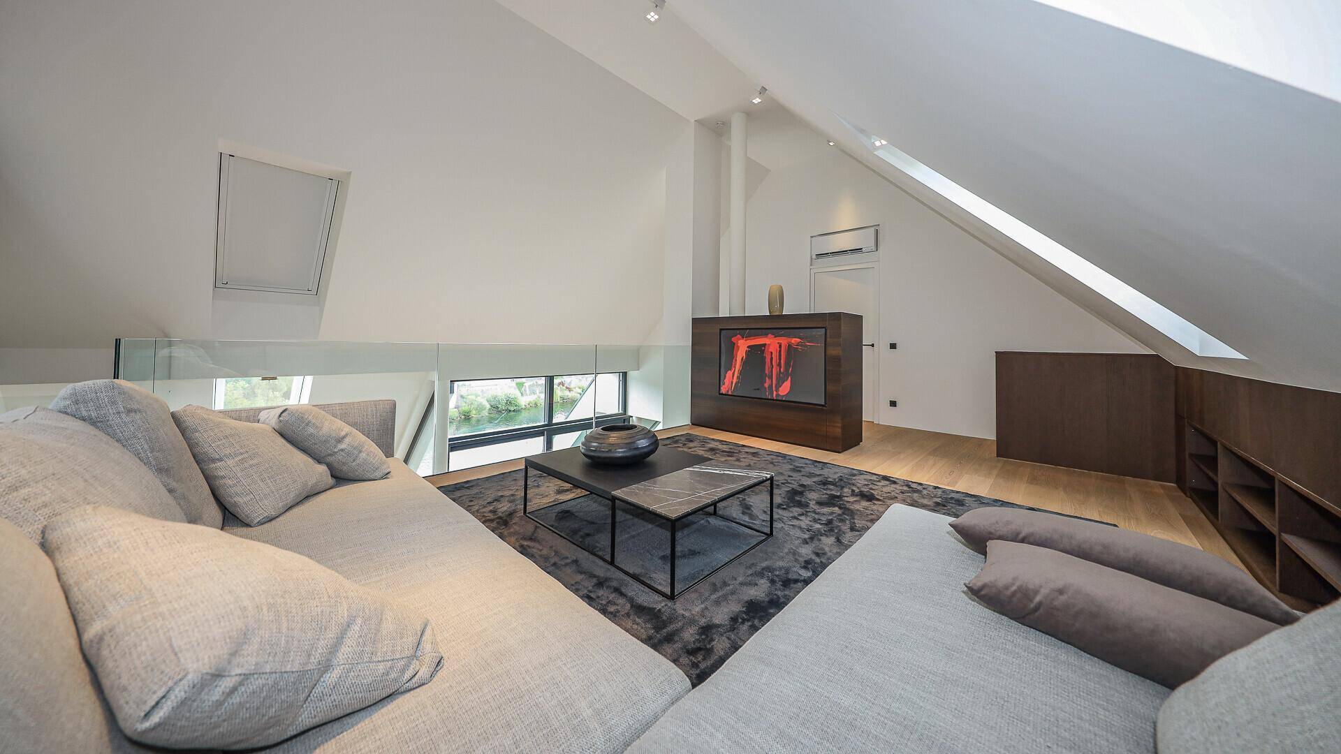 Modernes Wohnzimmer im Dachgeschoss mit schrägen Wänden, Dachfenstern und einem stilvollen Kamin.