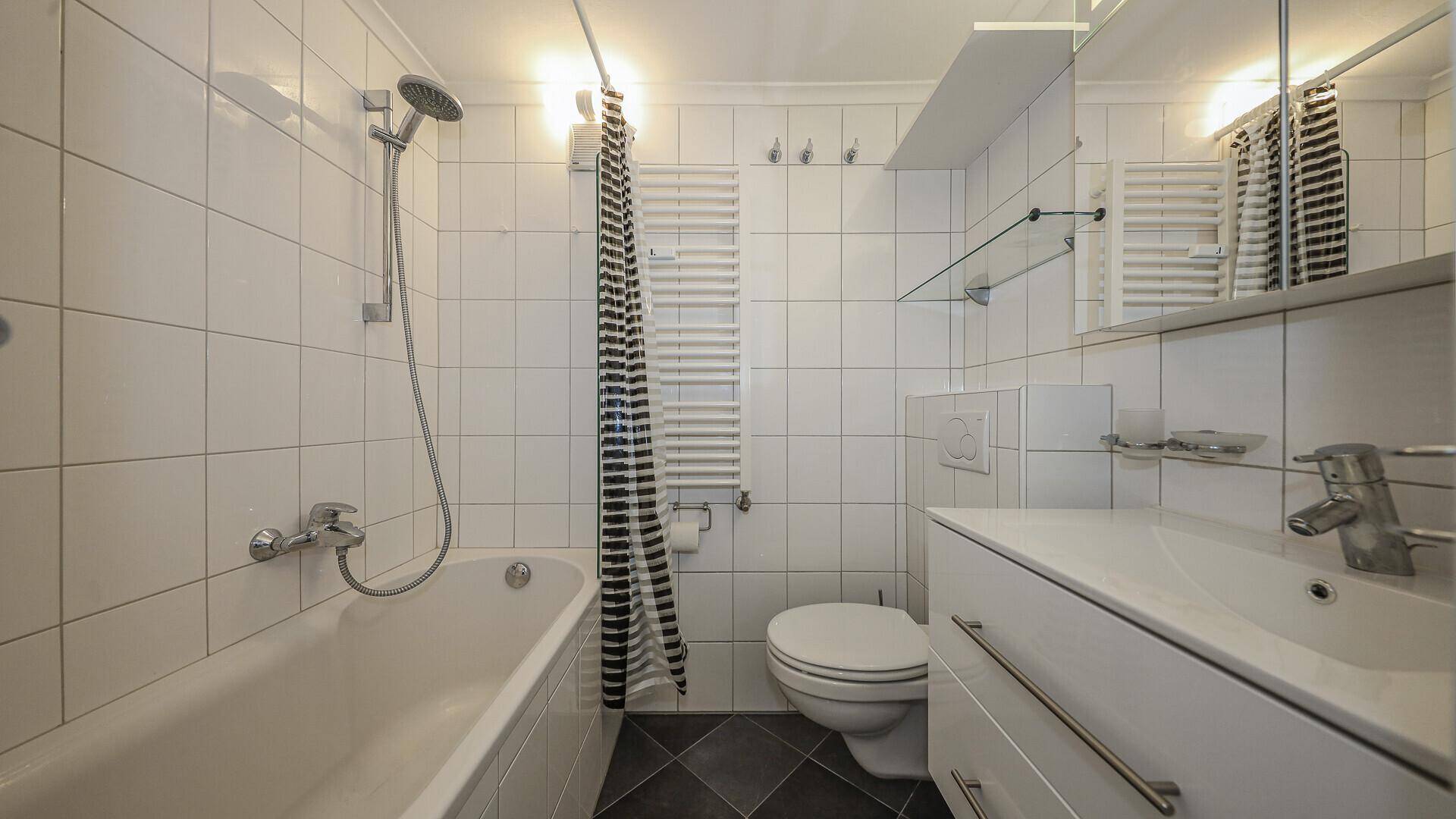 Helles Badezimmer mit Badewanne, Dusche, WC und beheiztem Handtuchhalter.