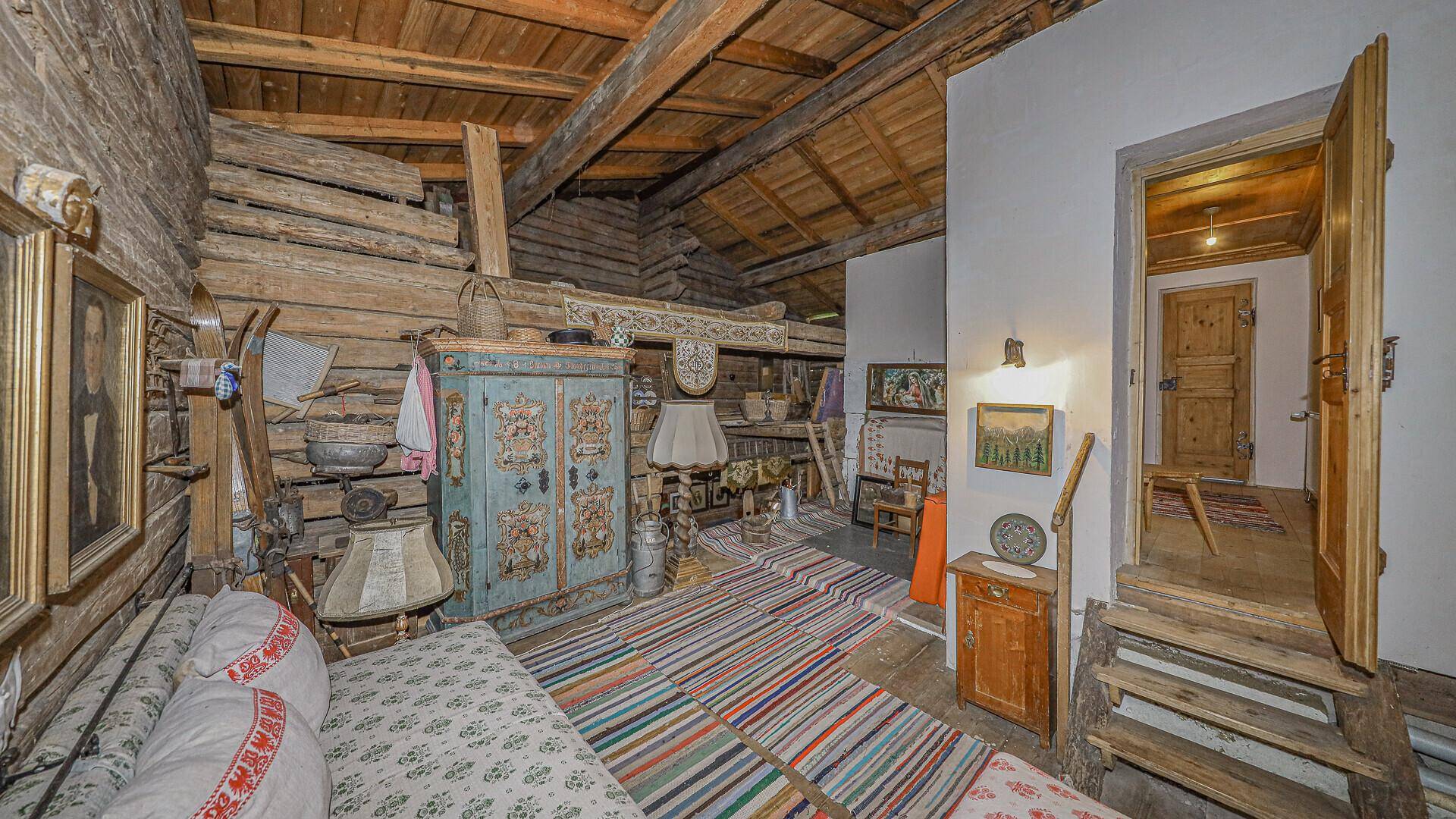 Rustikaler Wohnbereich im Originalzustand mit Holzbalken, Holzwänden und traditionellen Möbeln.