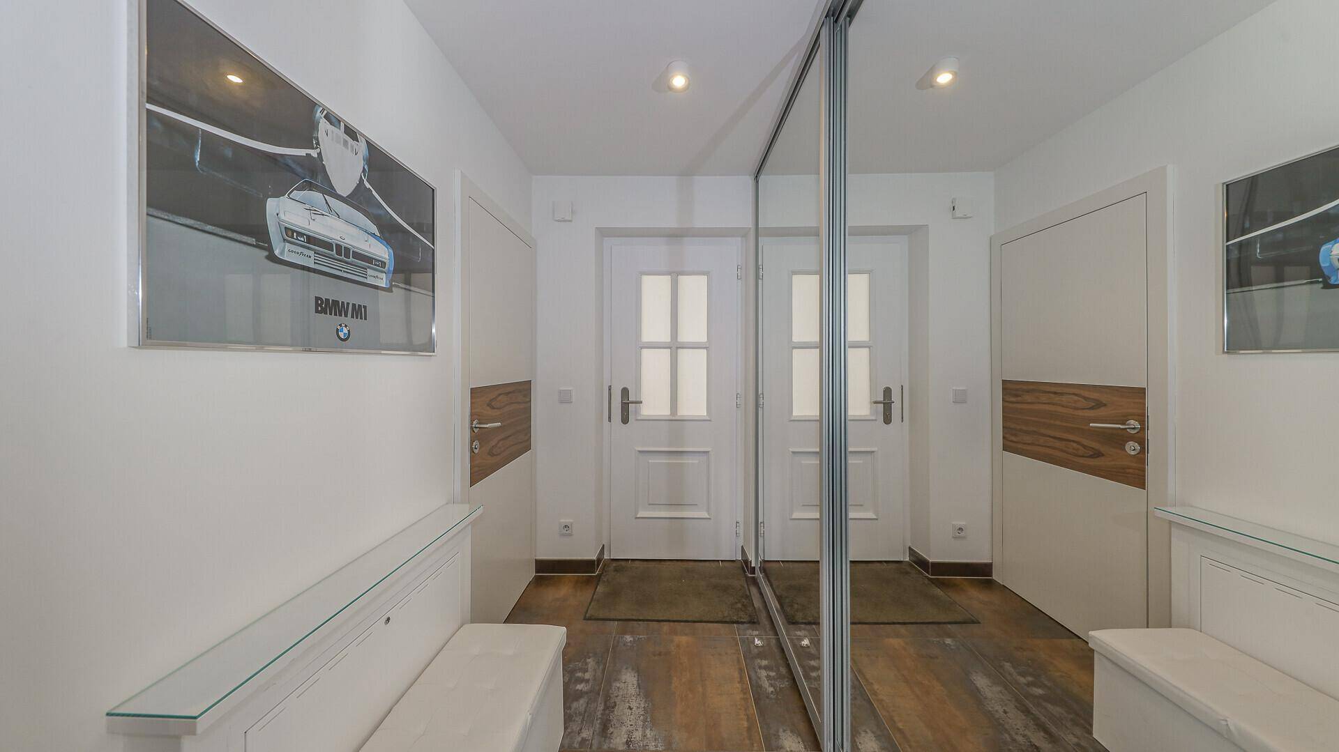 Geräumiger Flur mit großem Spiegelschrank, weißen Türen und praktischen Sitzbänken.