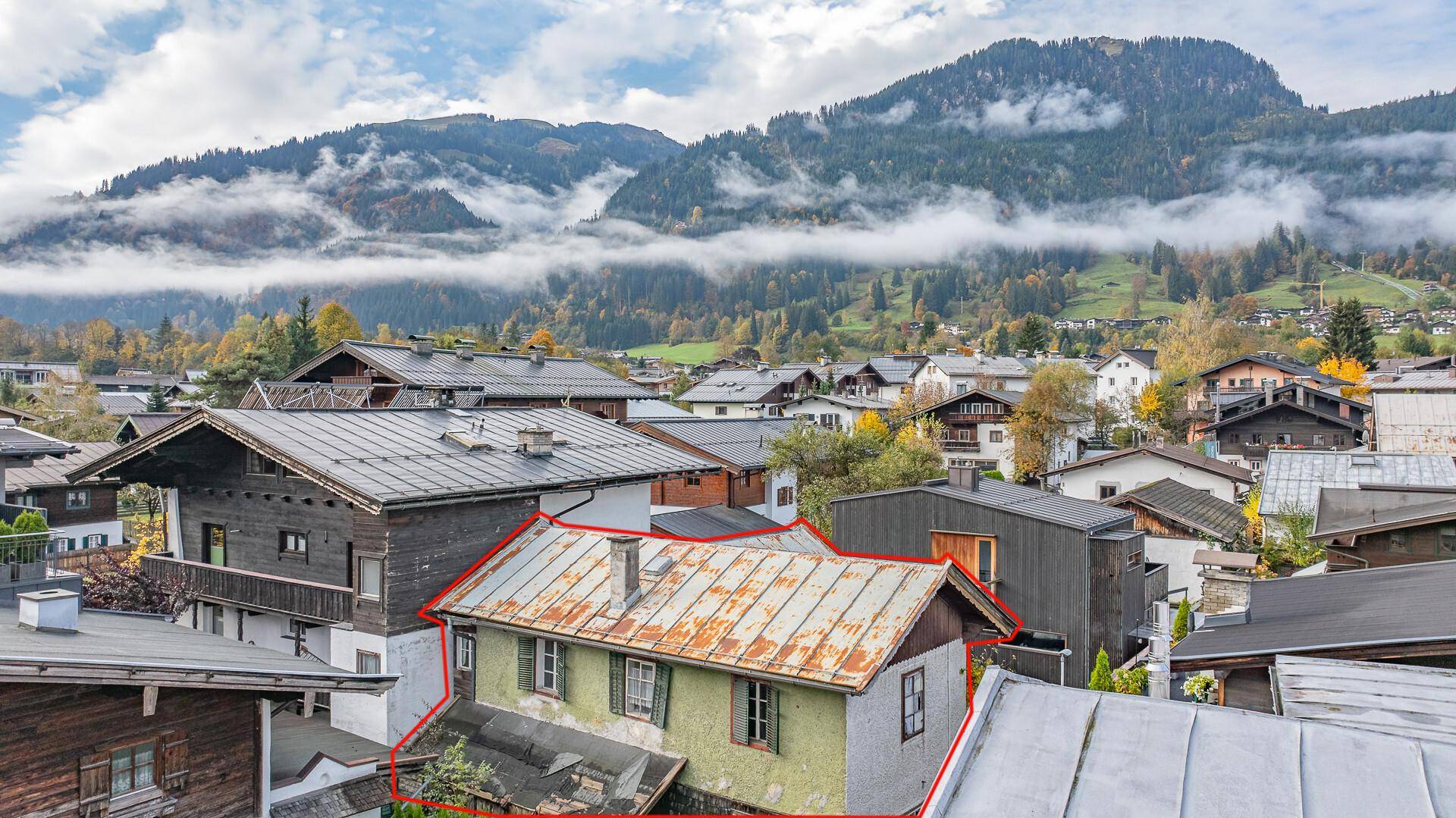 Panoramablick auf ein Haus mit rostigem Dach und die umliegende Berglandschaft.