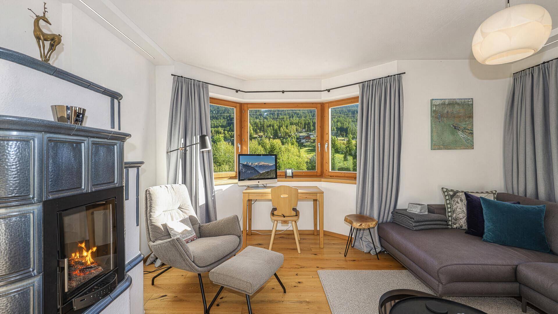 Gemütliche Leseecke im Wohnzimmer mit Schreibtisch, Kachelofen und weitem Blick ins Grüne.