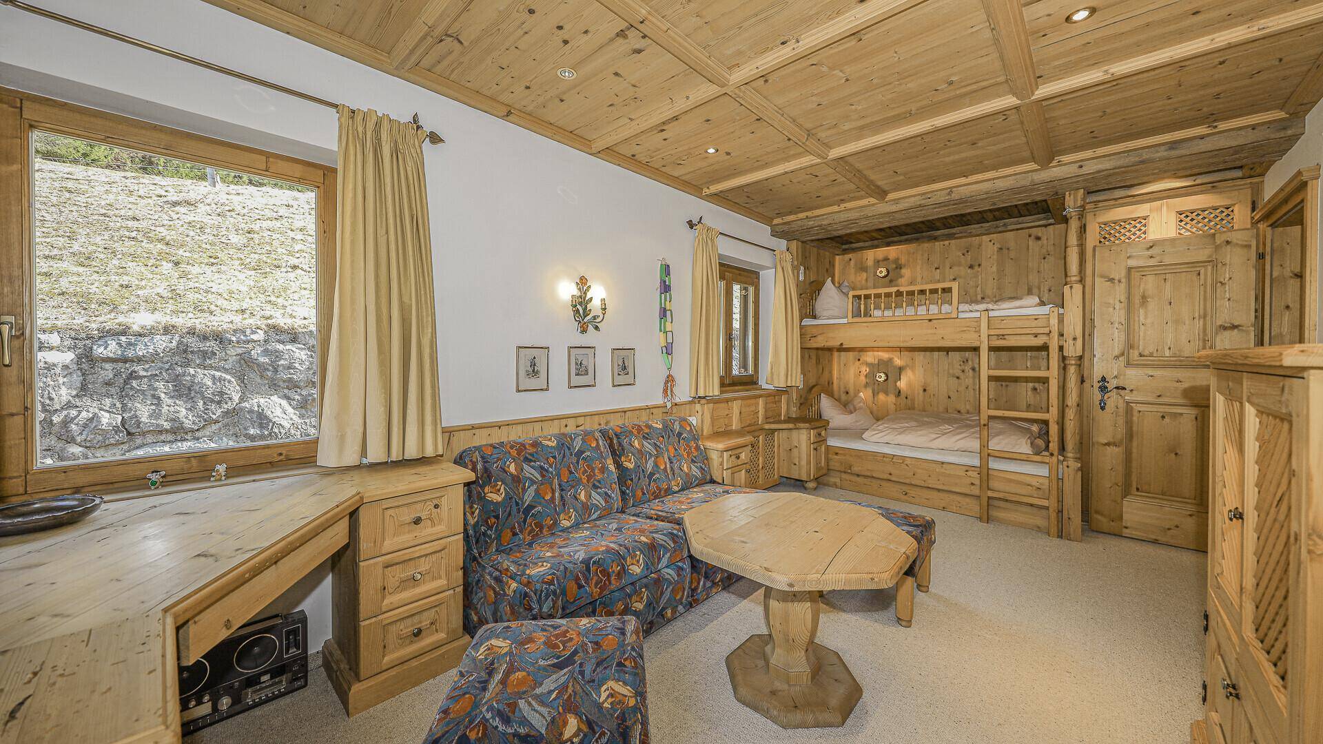 Kinder- oder Gästezimmer mit Etagenbett, Holzeinbauten und Blick auf die Landschaft.