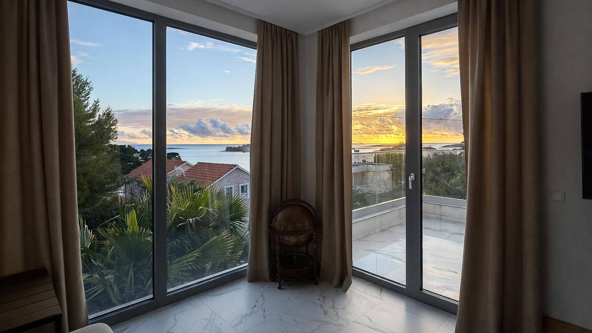 Raum mit großen Fensterfronten, die einen weiten Blick auf das Meer und die Umgebung bieten.