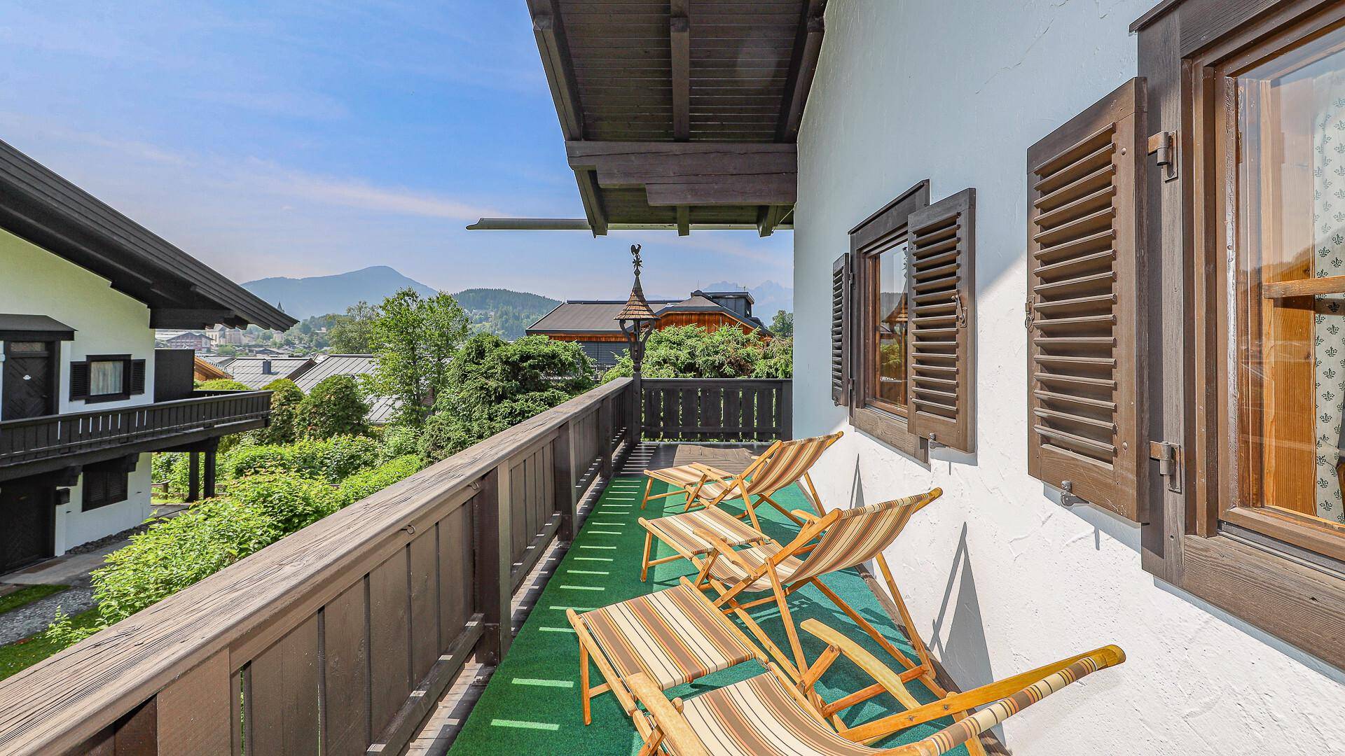 Sonniger Balkon mit Liegestühlen und Blick auf die umliegende Berglandschaft.