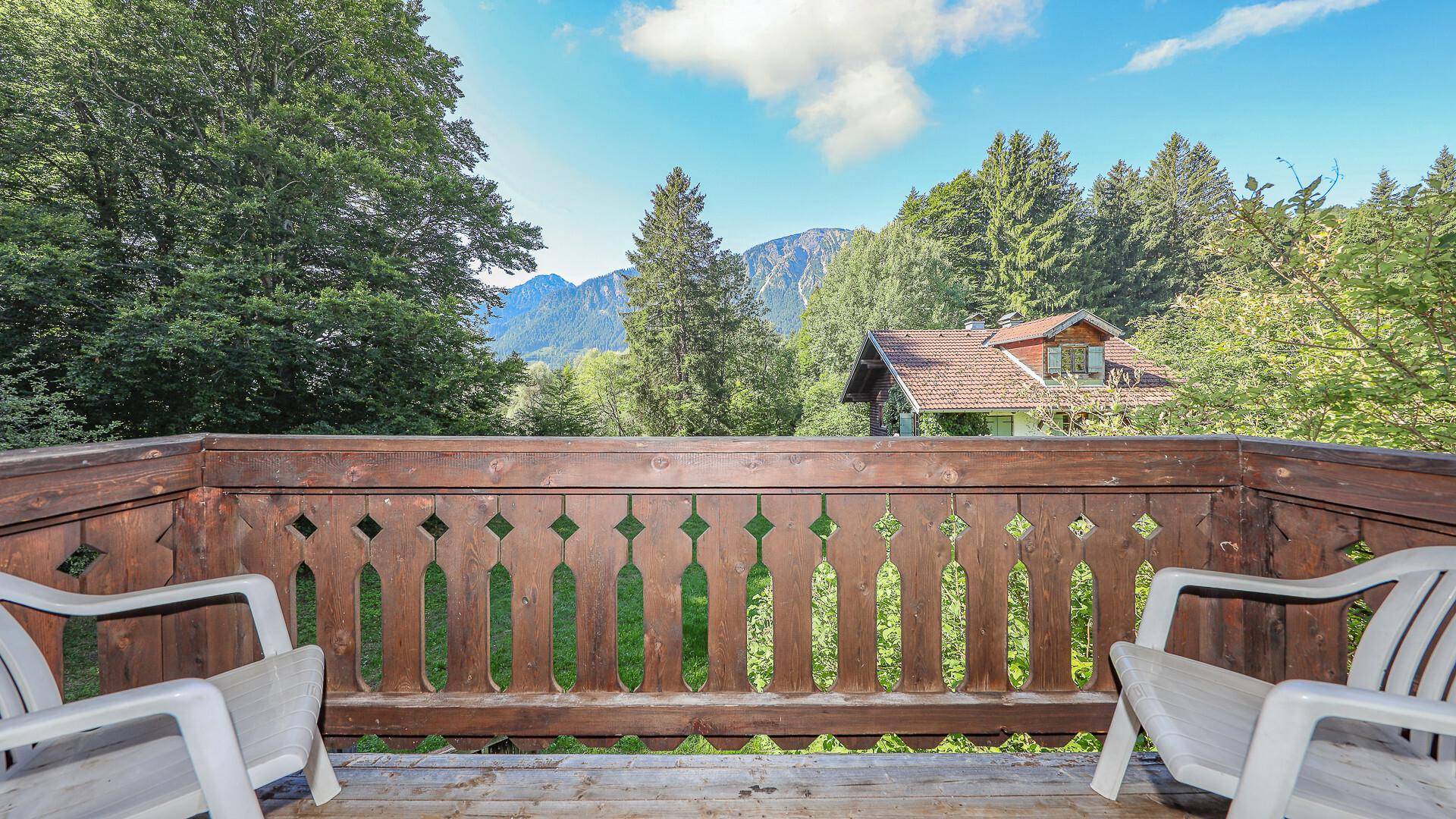 Balkon mit Holzbalkongeländer und zwei Stühlen, bietet einen schönen Blick auf die Berge.