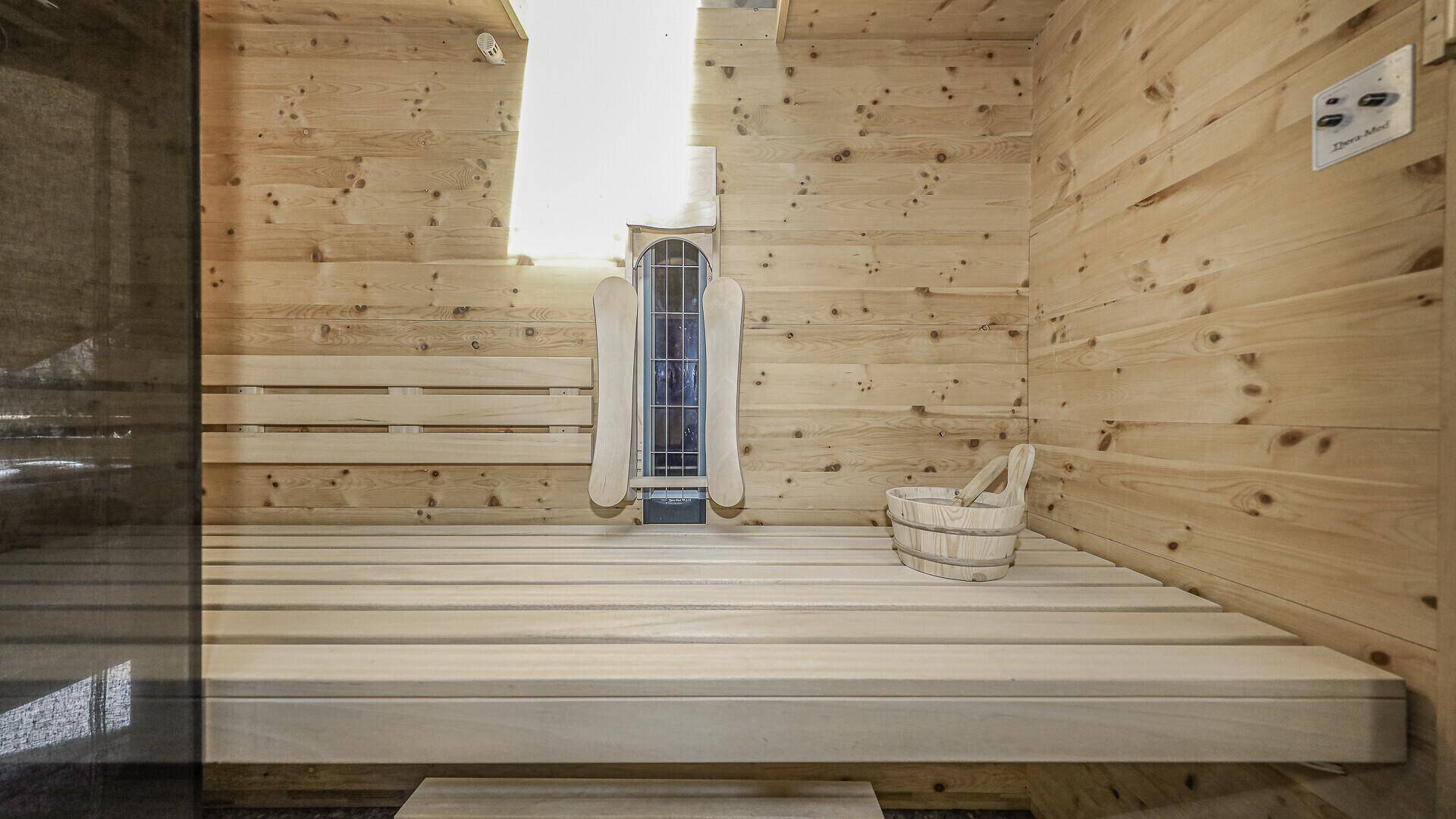 Traditionelle Holzsauna mit Bänken und Heizofen für entspannende Momente.