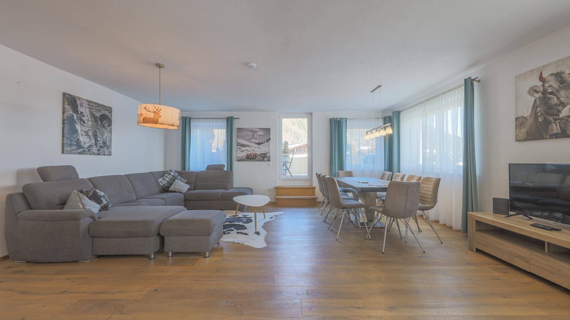 Heller Wohn-Essbereich mit großem Sofa, Esstisch und Blick ins Grüne.