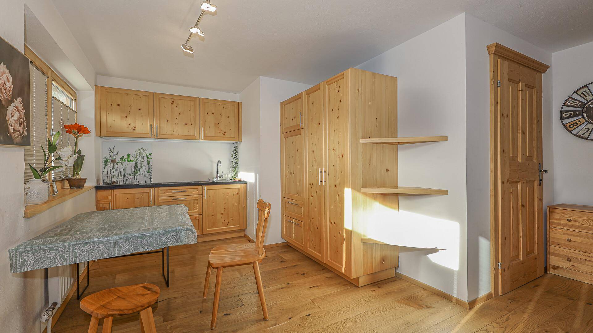Kleine Küche mit Holzelementen, Esstisch und viel natürlichem Licht durch das Fenster.