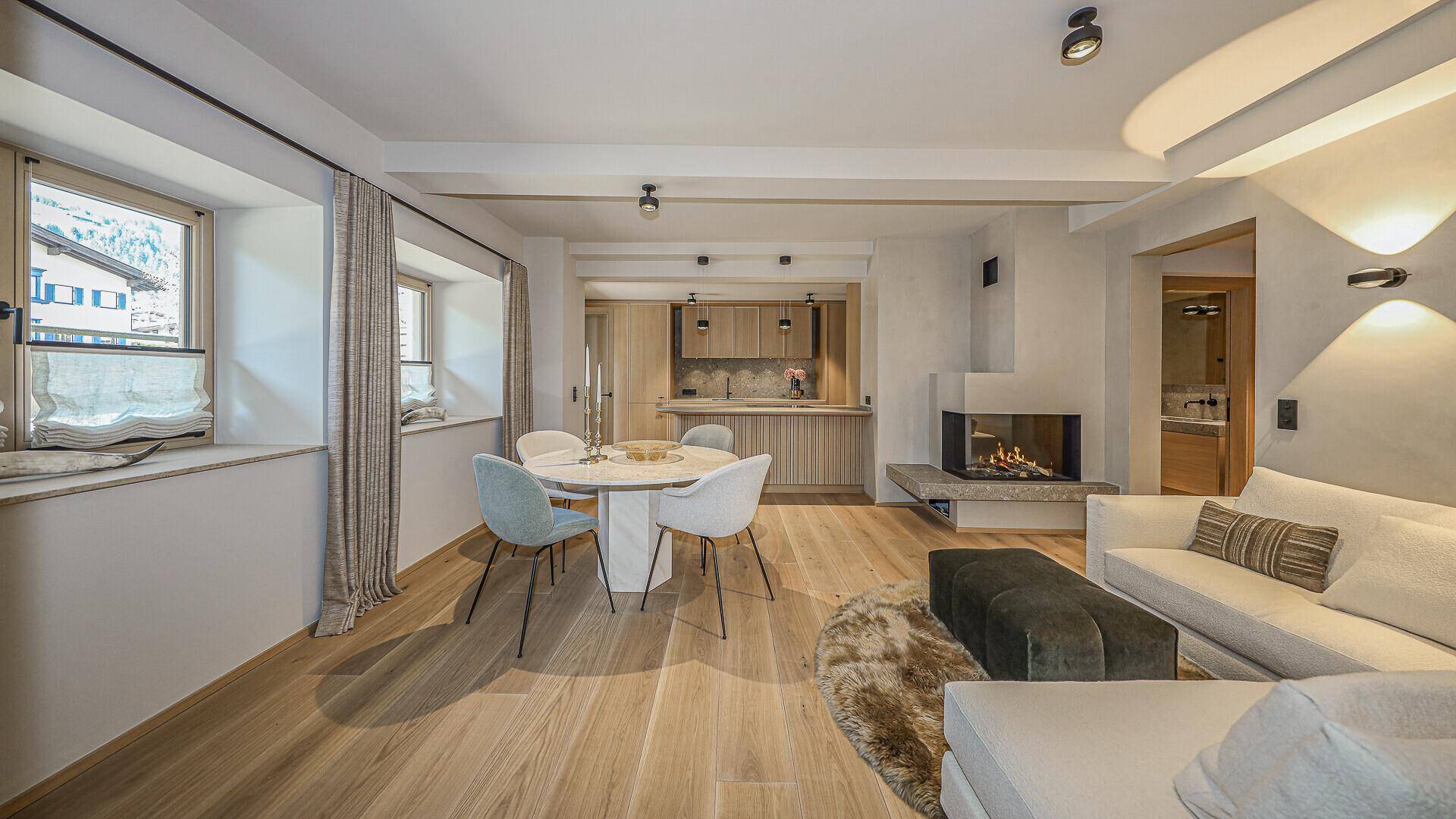 Stilvoller Wohn-Essbereich mit Kamin, Holzboden und moderner Einrichtung, verbunden mit der Küche.