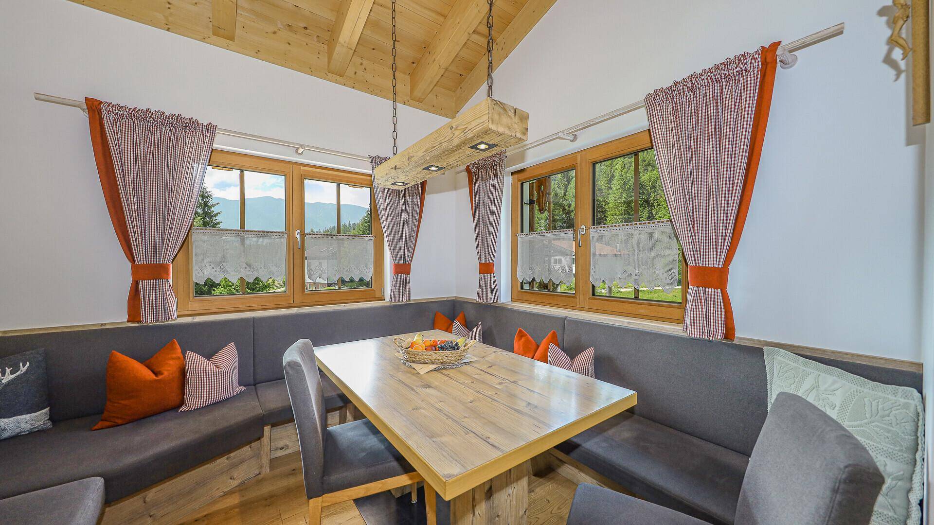 Lichtdurchfluteter Essbereich mit Eckbank, Holztisch und weitem Blick ins Grüne.