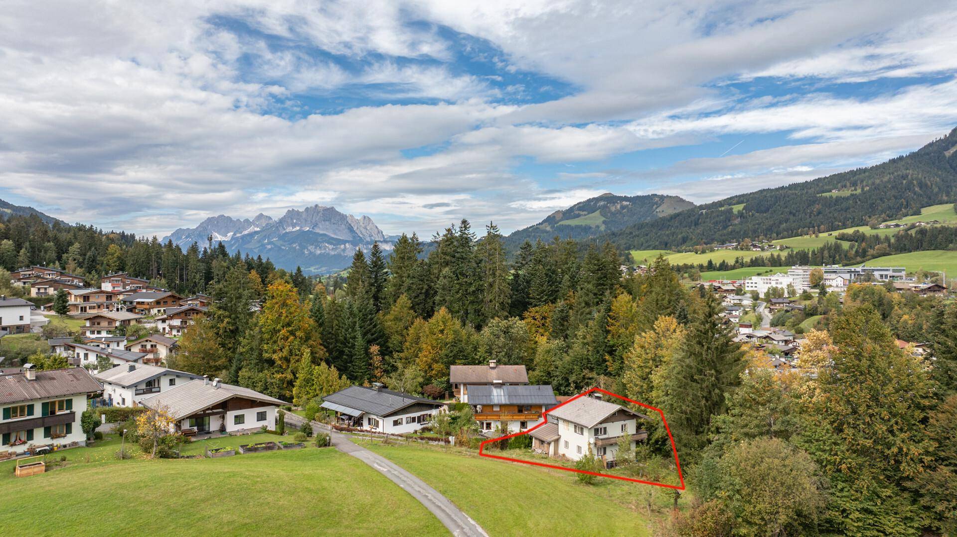 Luftaufnahme einer Wohnsiedlung in den Bergen, mit einem roten Rahmen, der ein bestimmtes Haus hervorhebt.