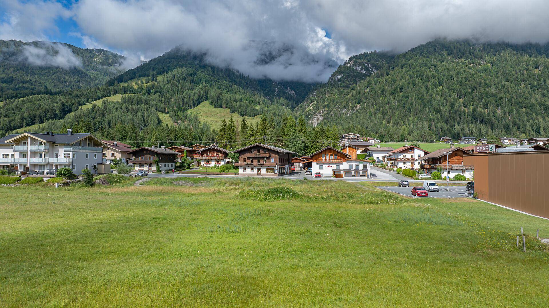 Panoramablick auf eine ländliche Wohnsiedlung eingebettet in eine malerische Berglandschaft.