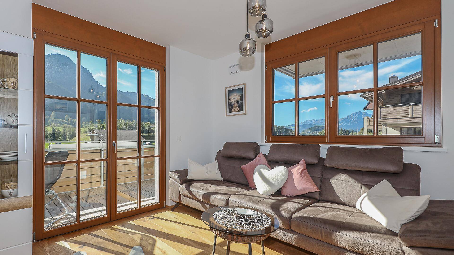 Gemütliches Wohnzimmer mit bequemer Couch, Holzboden und direktem Zugang zum Balkon.