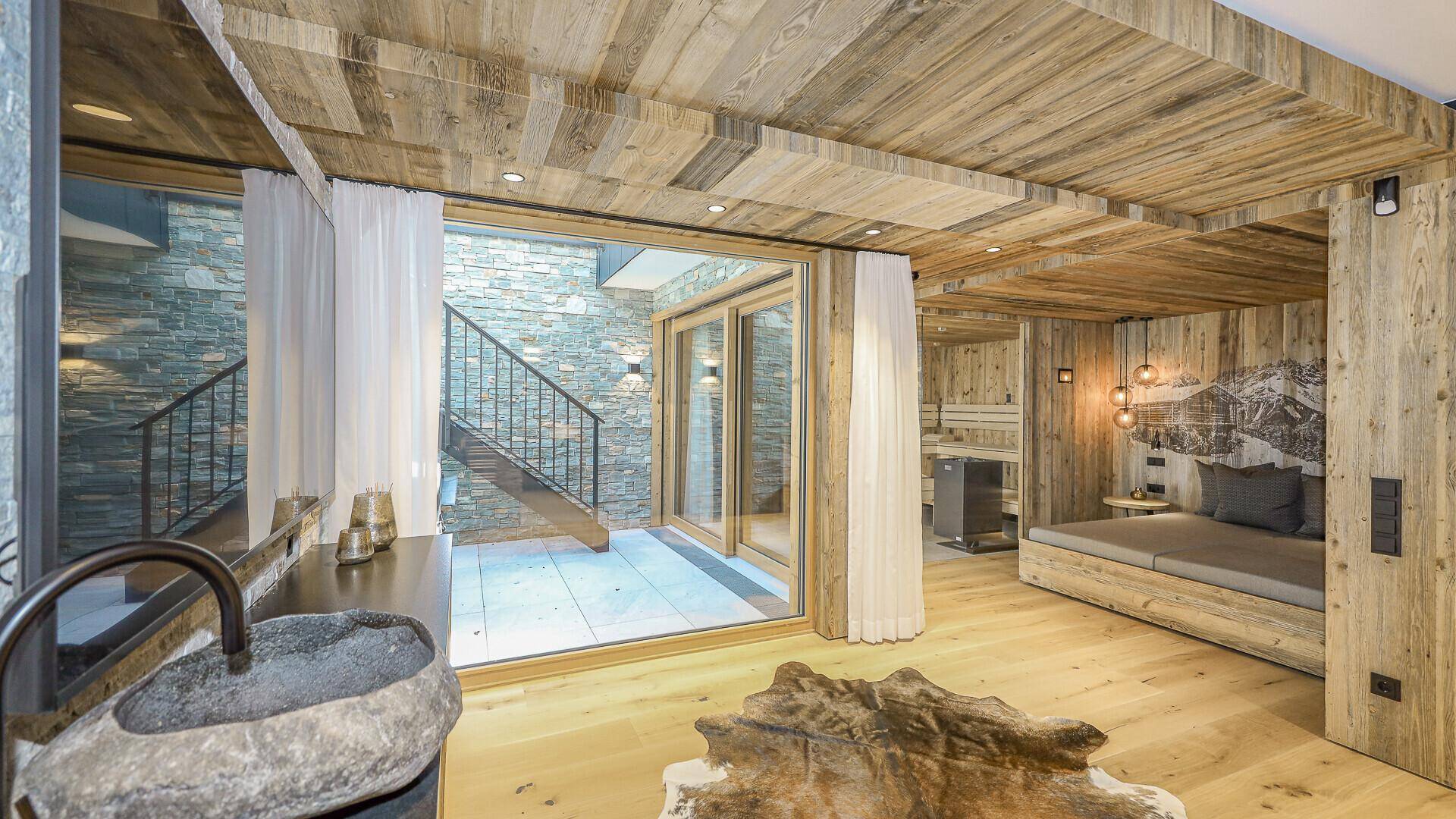 Luxuriöses Schlafzimmer mit Holzelementen, Steinwaschbecken und integrierter Sauna.