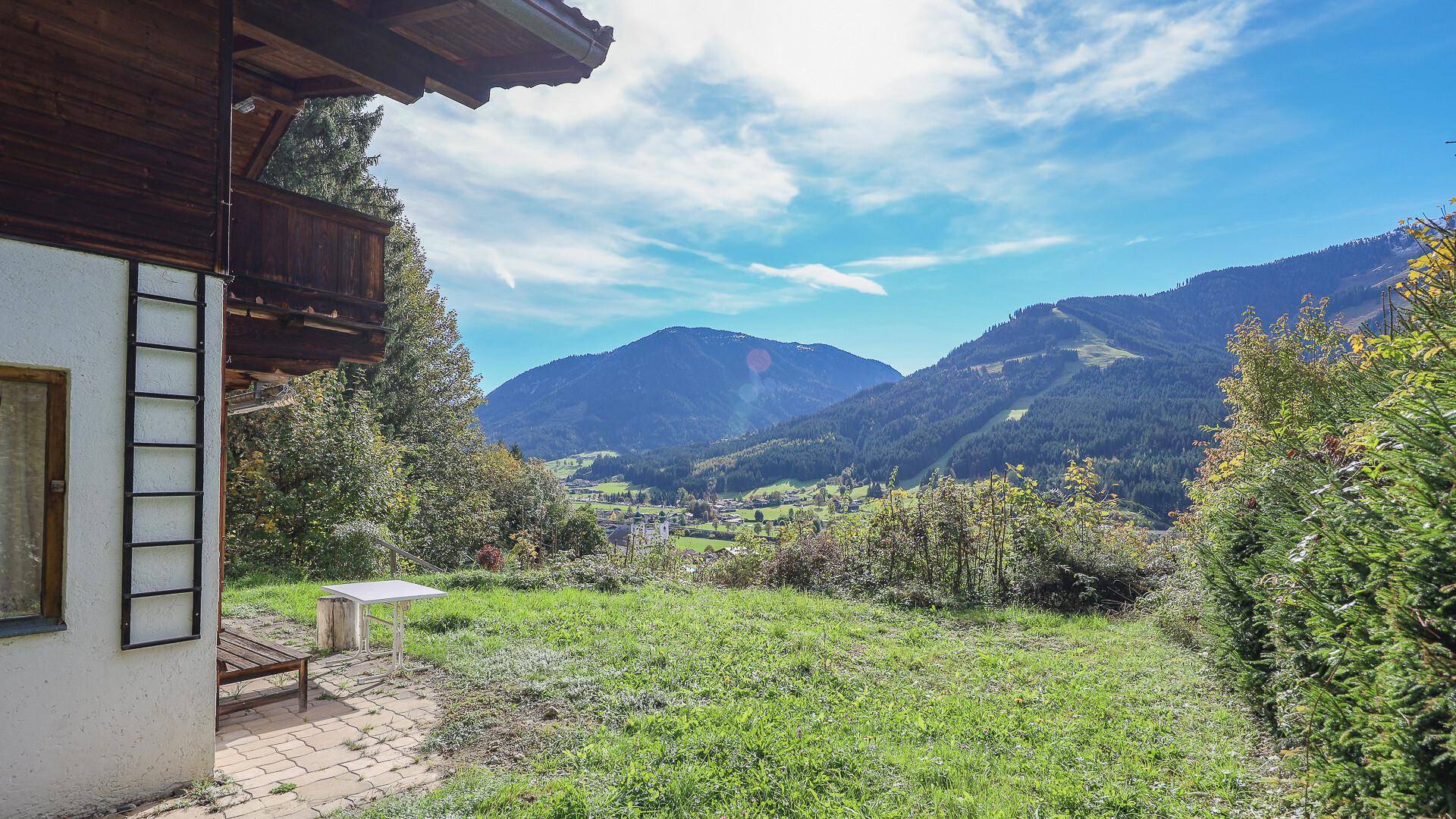 Gartenbereich mit Rasen und Terrasse, bietet einen weiten Blick auf die umliegende Berglandschaft.