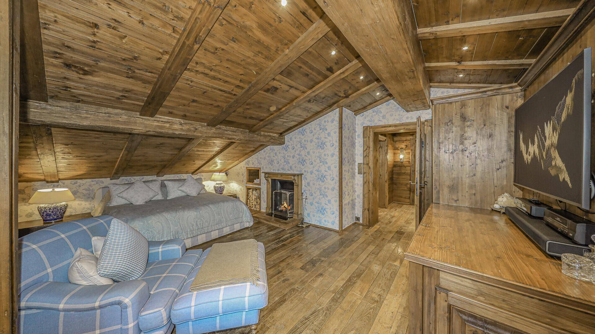 Schlafzimmer im Dachgeschoss mit Holzbalkendecke, Kamin und gemütlicher Sitzecke.