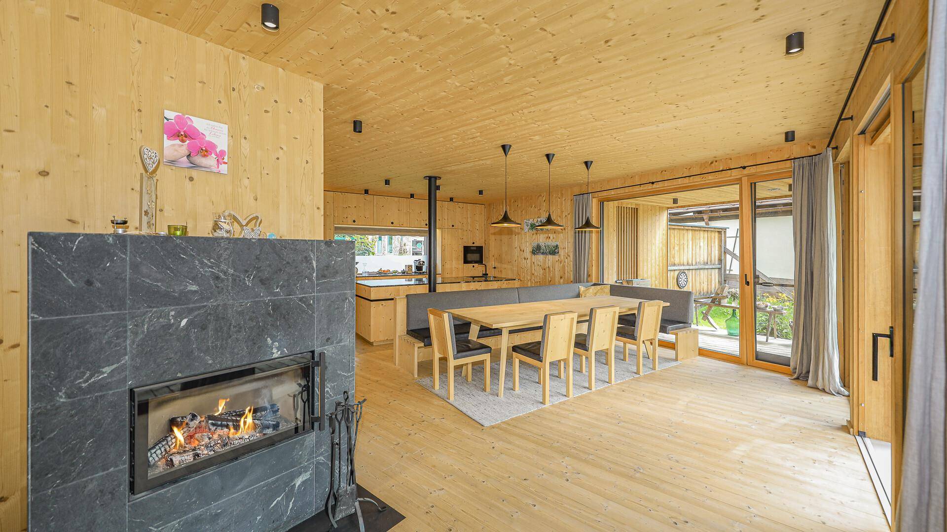 Gemütlicher Wohn- und Essbereich mit Kamin, Holzeinrichtung und Blick auf den Garten.