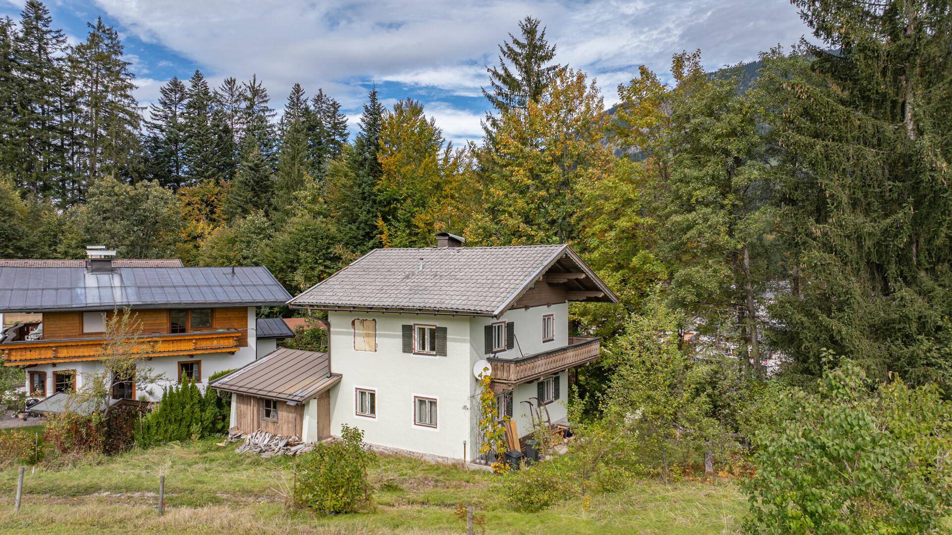 Ein charmantes Haus im Grünen, umgeben von Bäumen und Wiesen, mit traditioneller Architektur.