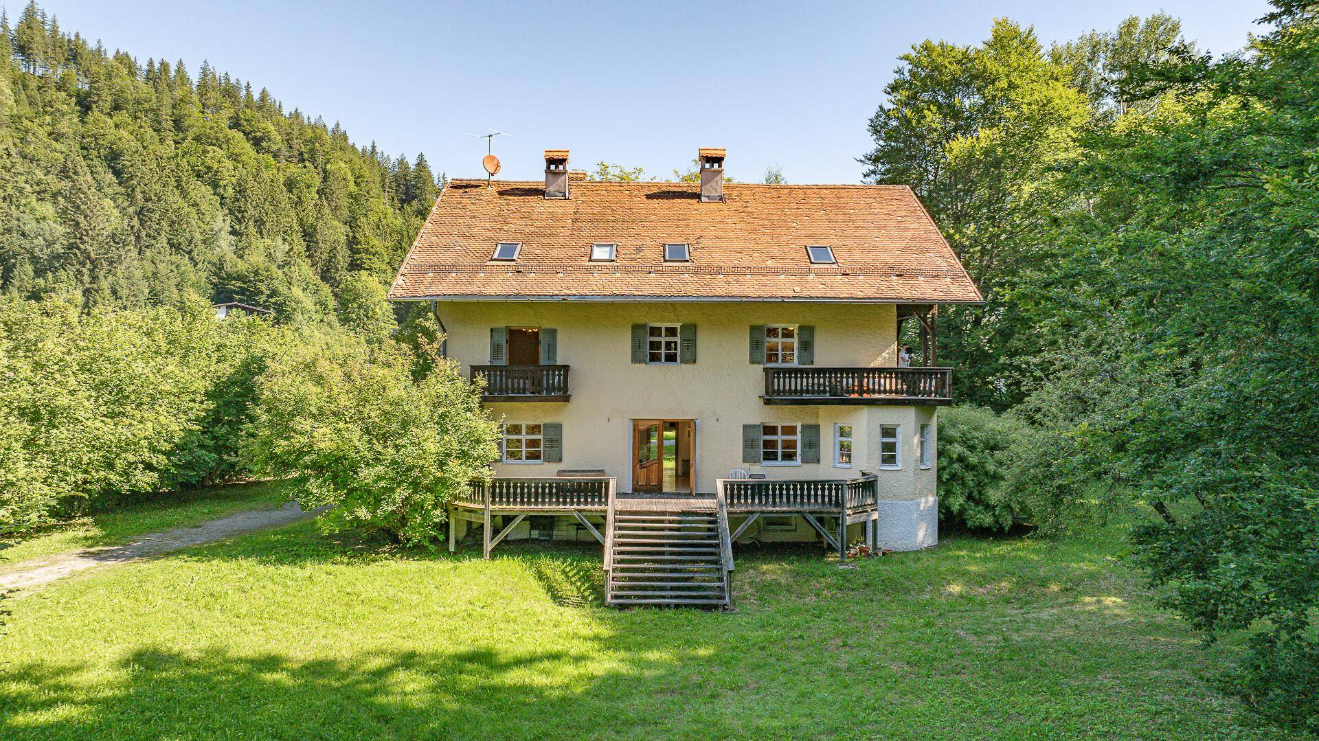 Vorderansicht des Hauses mit großer Holzterrasse und Treppe zum Gartenbereich.