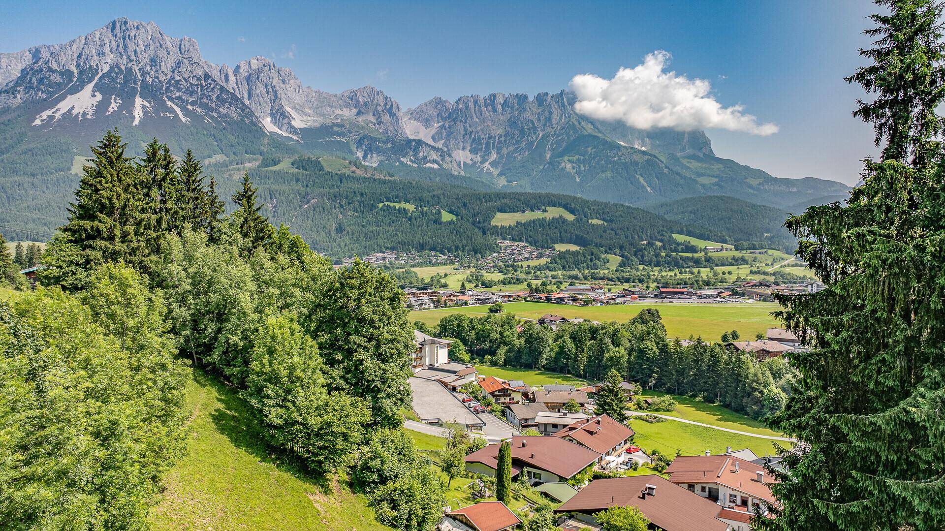 Spektakulärer Panoramablick auf die majestätischen Alpen und ein grünes Tal mit Siedlungen.