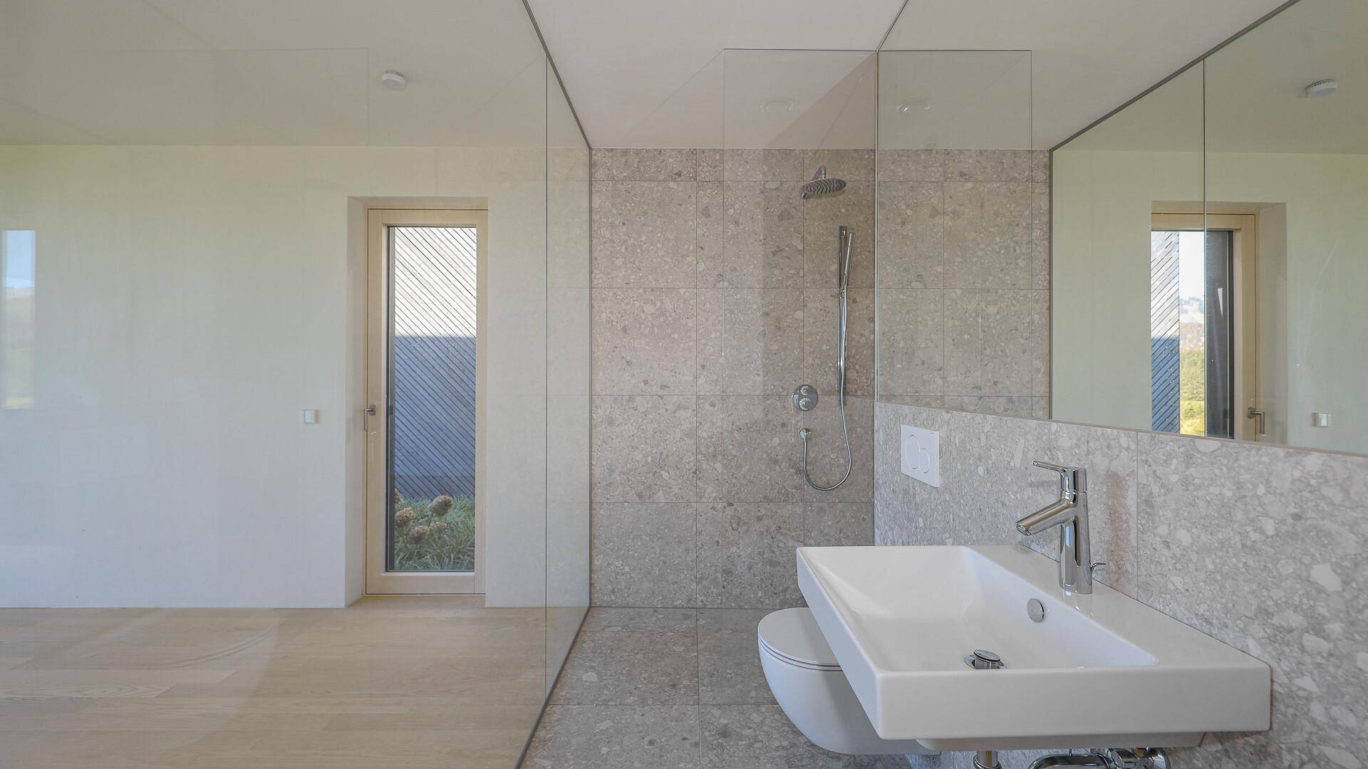Modernes Badezimmer mit Fliesenboden, begehbarer Dusche und Fenster zur Natur.