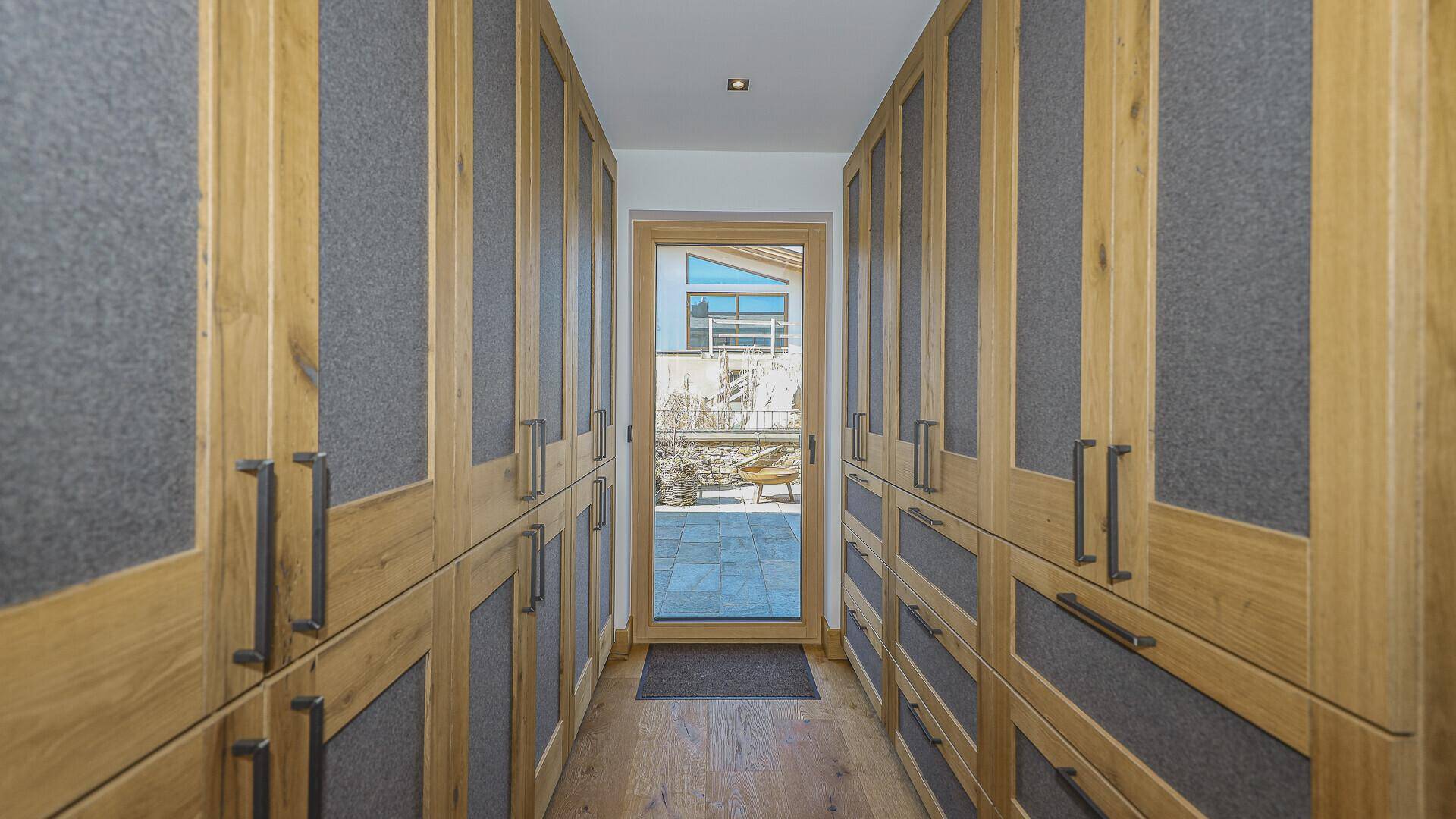 Geräumiger begehbarer Kleiderschrank mit maßgefertigten Holzschränken und Tageslicht.