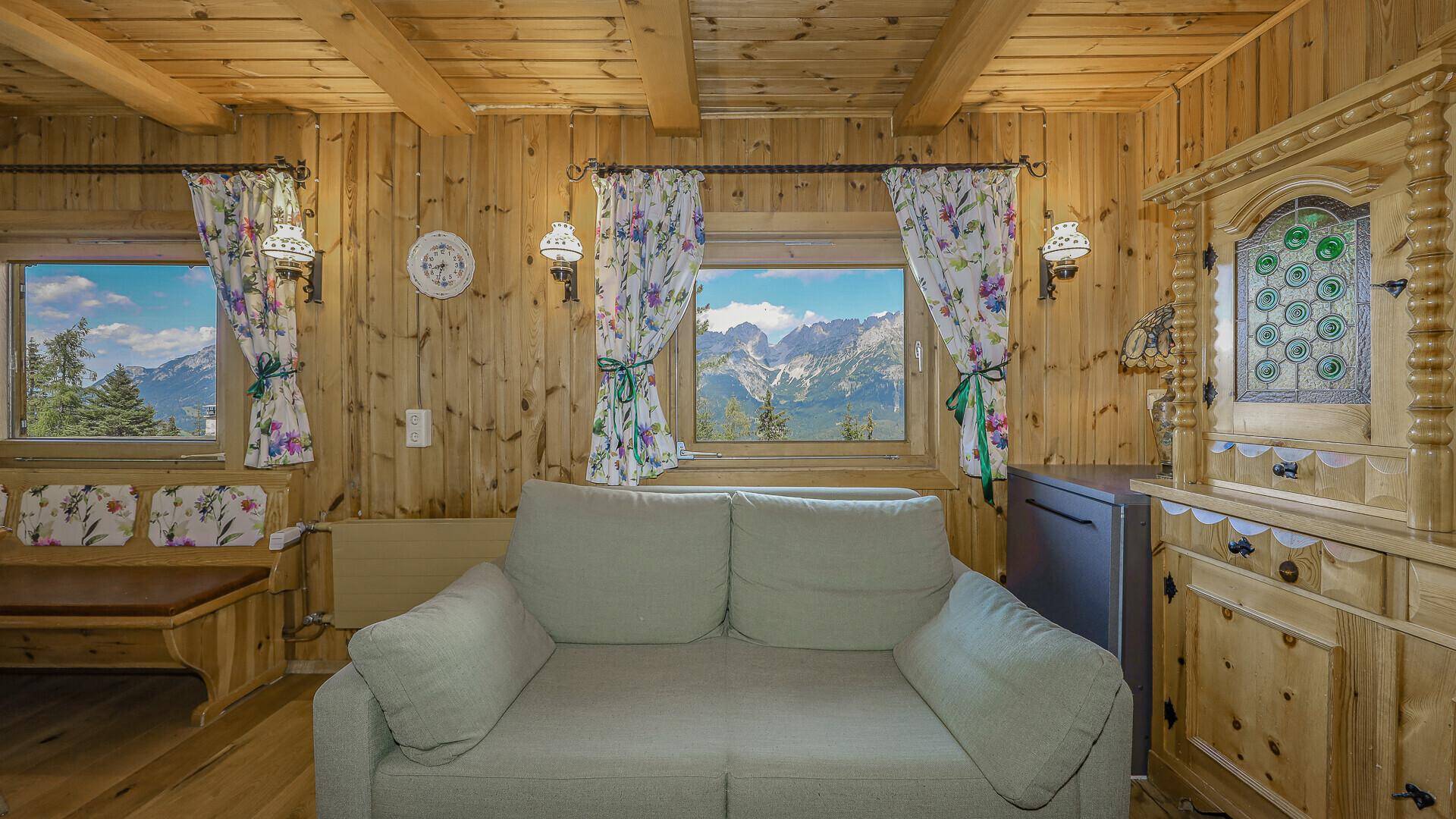 Wohnbereich im Chalet mit bequemer Couch, Fenstern mit Bergblick und einem traditionellen Holzschrank.