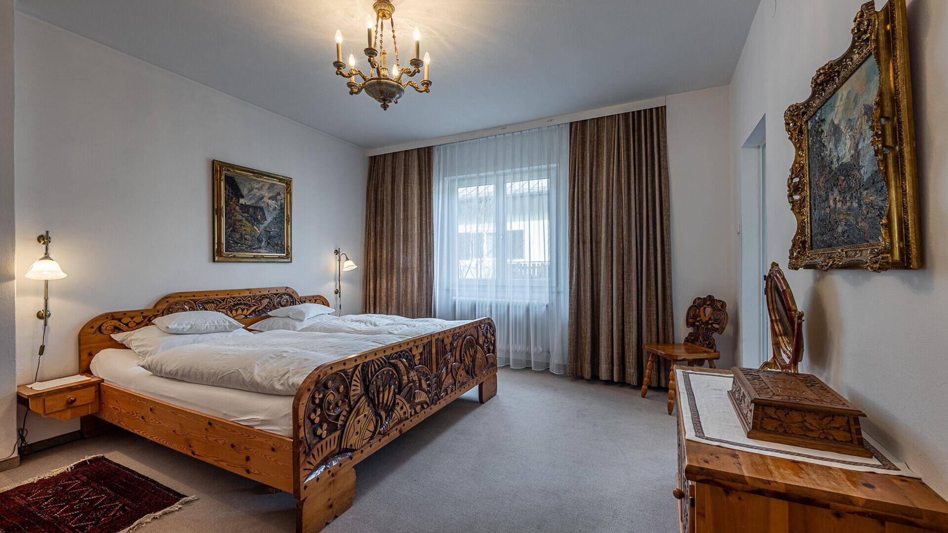 Traditionelles Schlafzimmer mit kunstvoll geschnitztem Holzbett und klassischer Einrichtung.