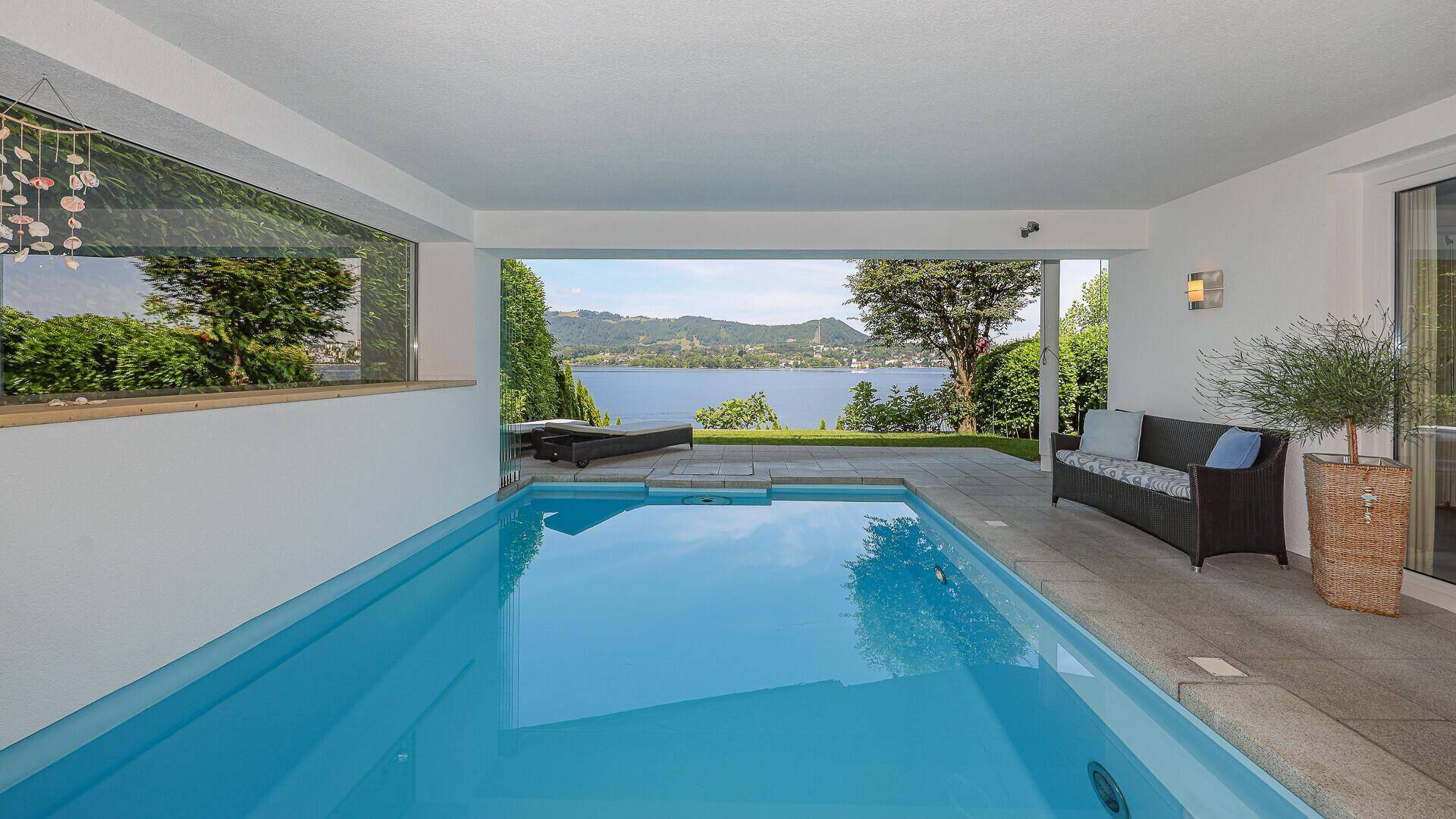 Überdachter Poolbereich mit Liegemöglichkeiten und direktem Blick auf den malerischen See.
