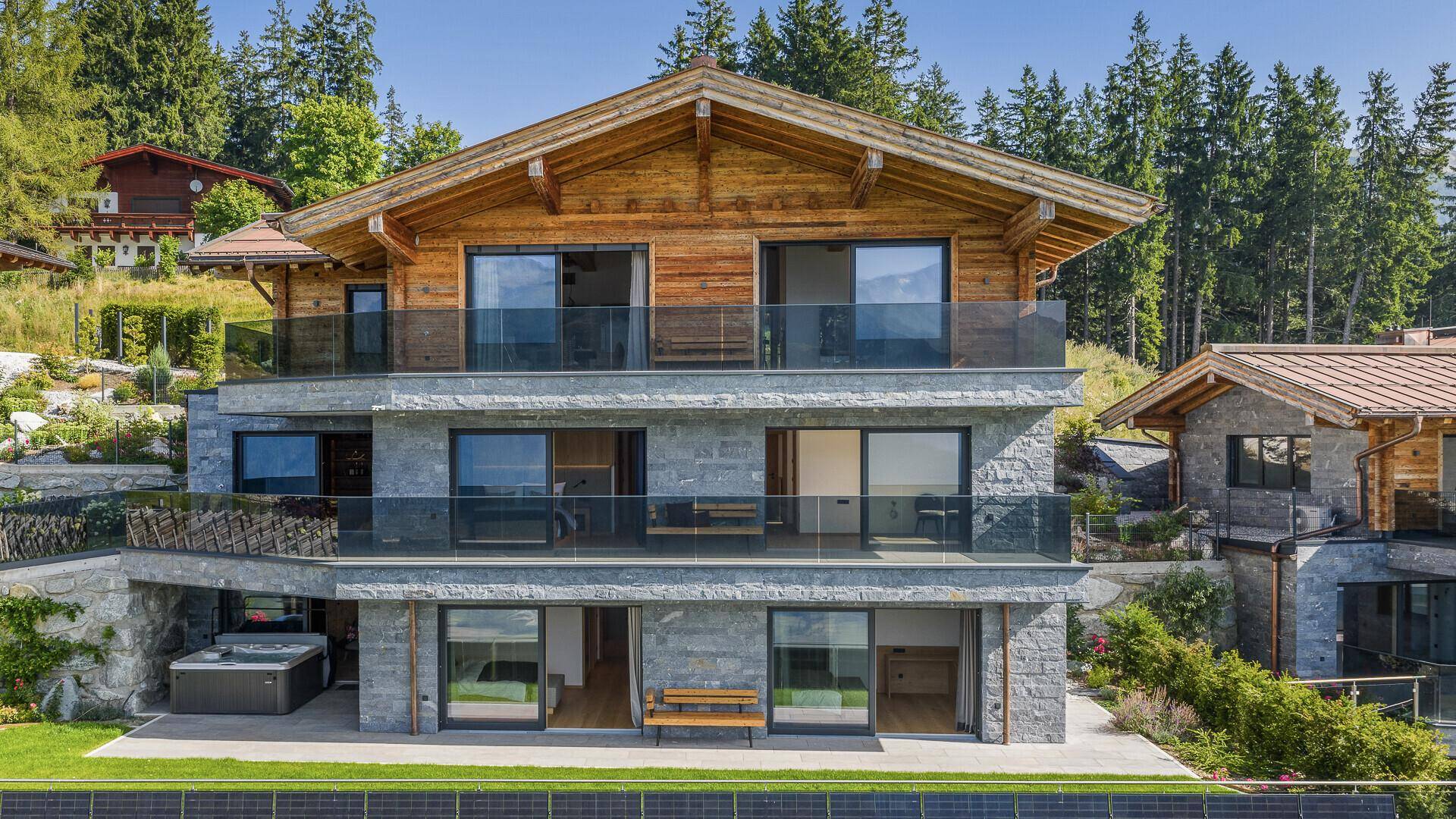 Luxuriöses Chalet mit moderner Architektur, Stein- und Holzfassade, umgeben von alpiner Landschaft.