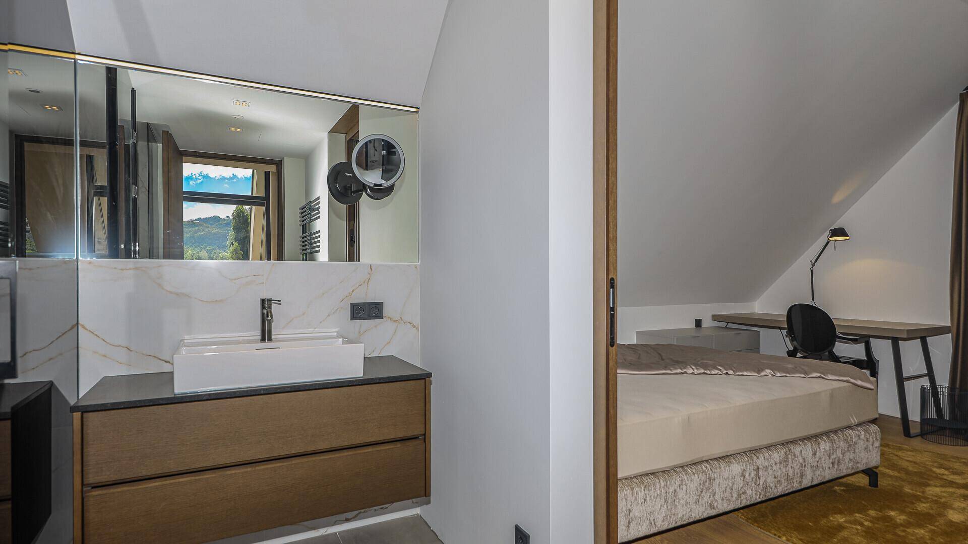 Modernes Badezimmer mit Einzelwaschbecken und Blick aus dem Fenster ins Grüne.