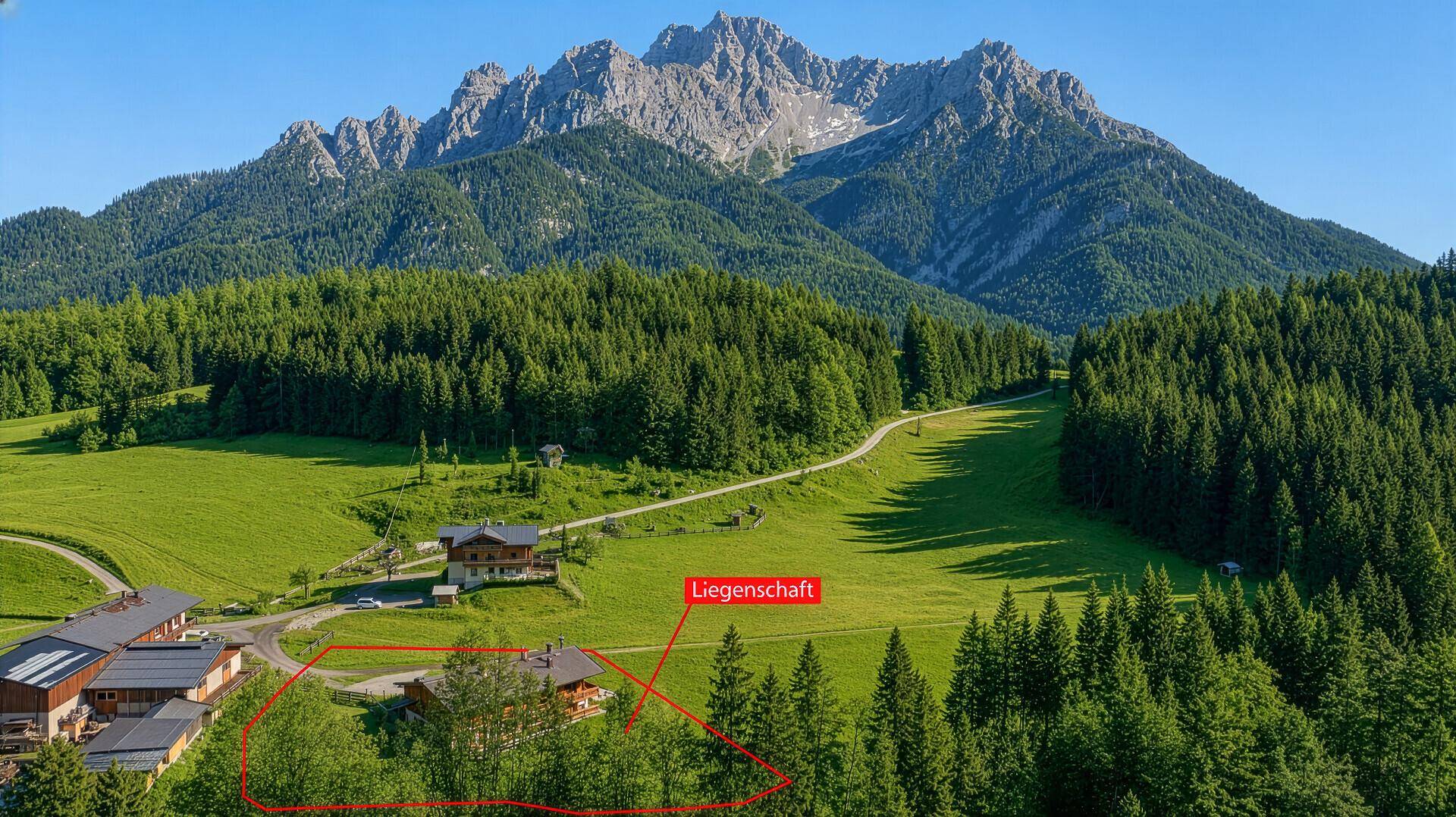 Luftaufnahme der Liegenschaft in einer weiten Berglandschaft mit Wäldern und Wiesen.