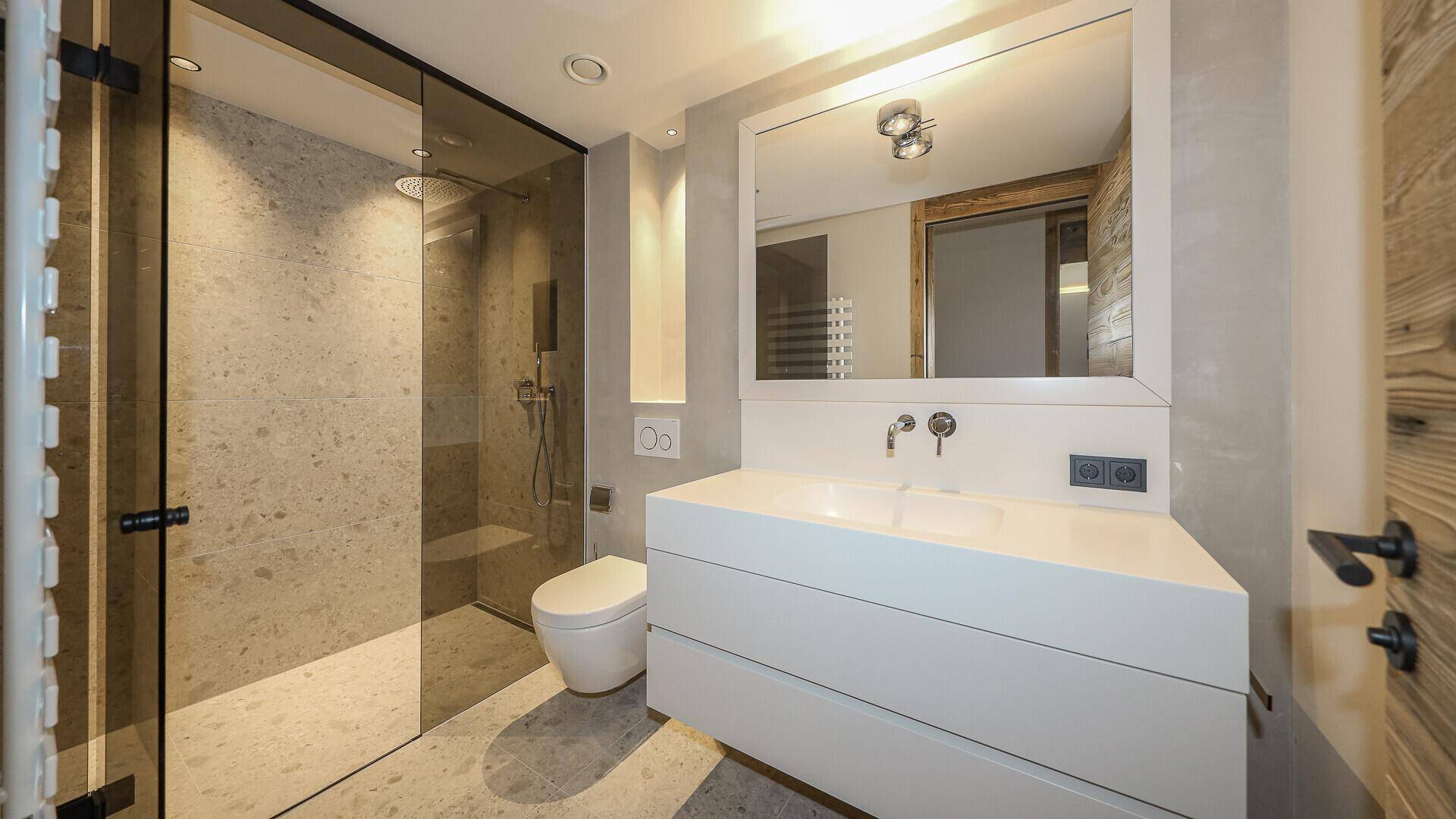 Modernes Badezimmer mit begehbarer Dusche, wandhängendem WC und Einzelwaschbecken.