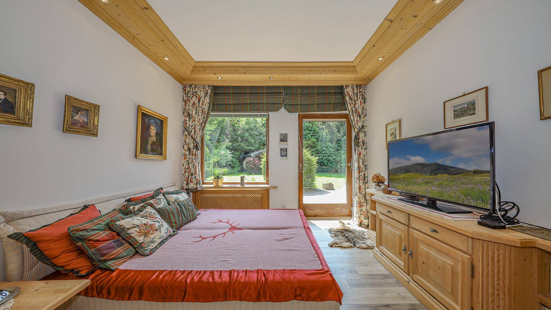 Helles Schlafzimmer mit Holzbalkendecke, zwei Einzelbetten und Zugang zum Garten.