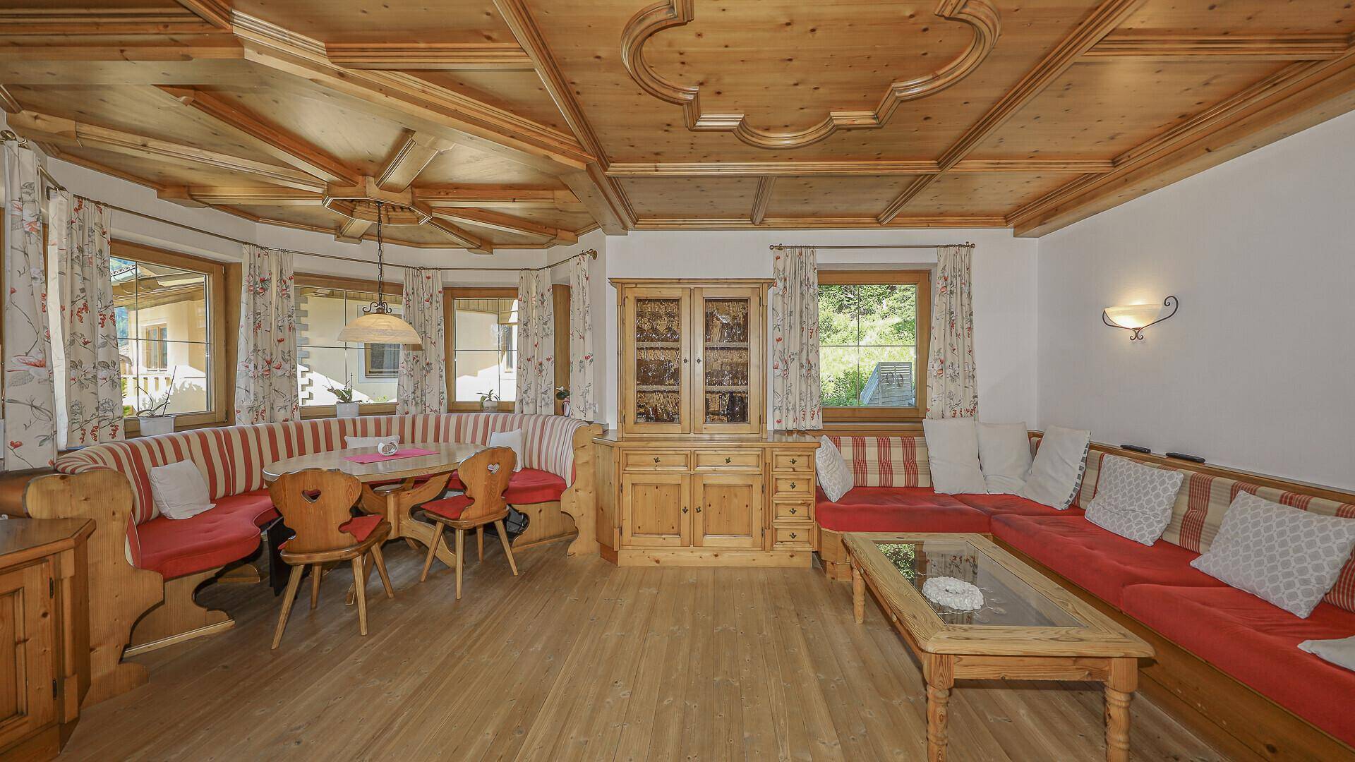 Traditioneller Wohn- und Essbereich mit Holzbalkendecke, Eckbank und gemütlicher Sitzecke.