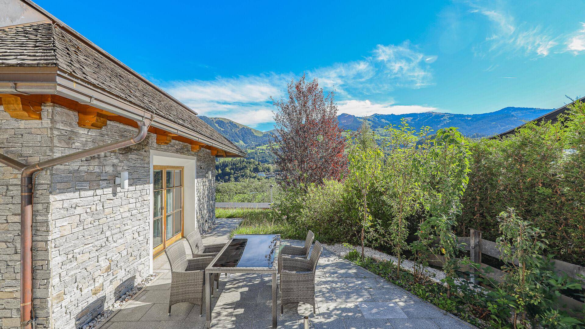 Gemütliche Steinterrasse mit Outdoor-Möbeln und einem herrlichen Blick auf die alpine Landschaft.