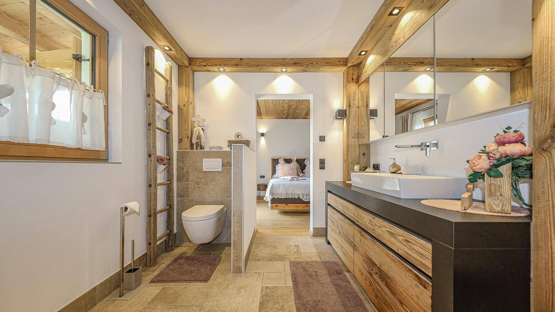 Elegantes Badezimmer mit Waschtisch, wandhängendem WC und Zugang zum Schlafzimmer.