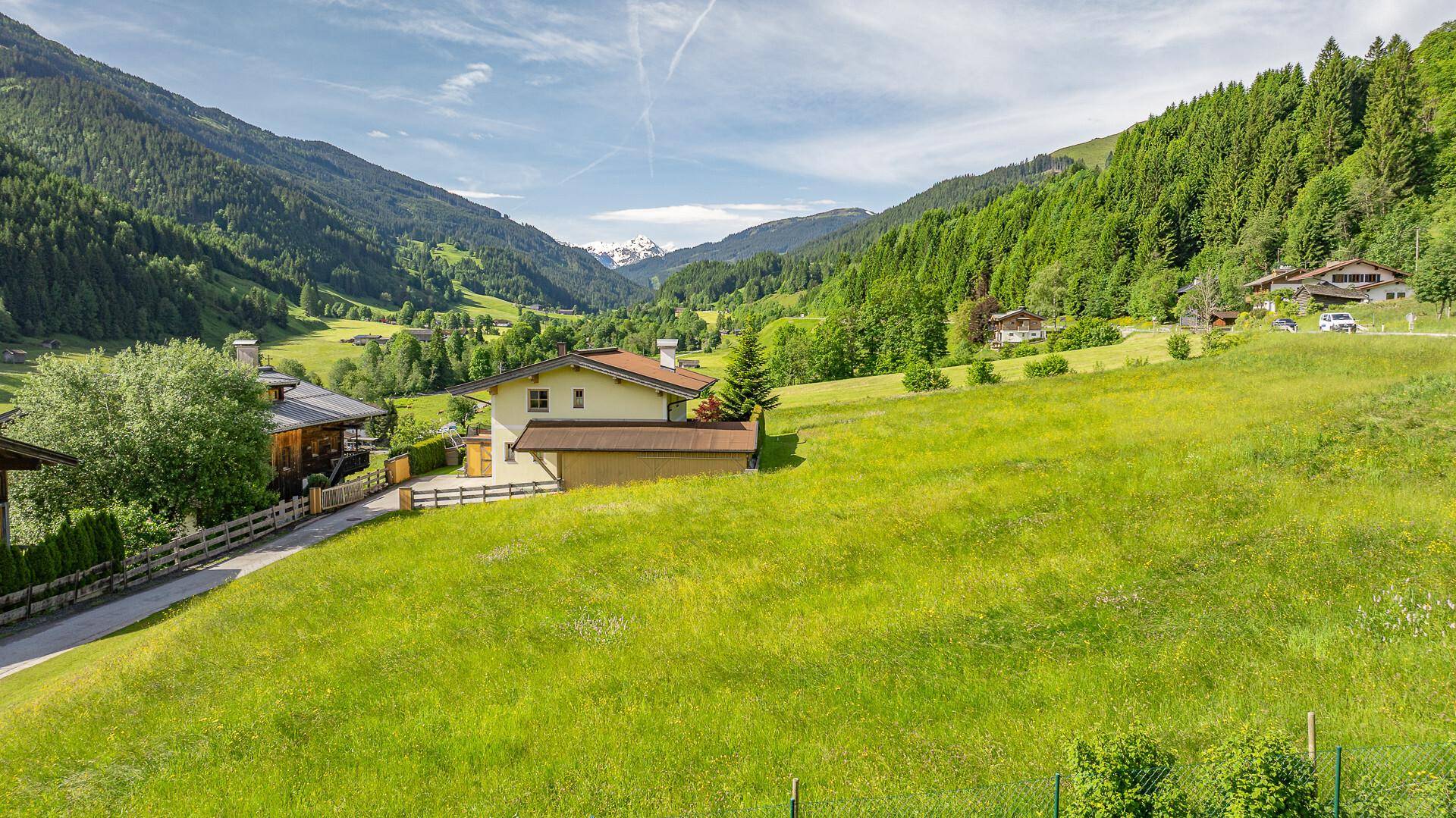 Idyllische Berglandschaft mit grünen Wiesen und Wäldern, einem Haus und einem weiten Horizont.