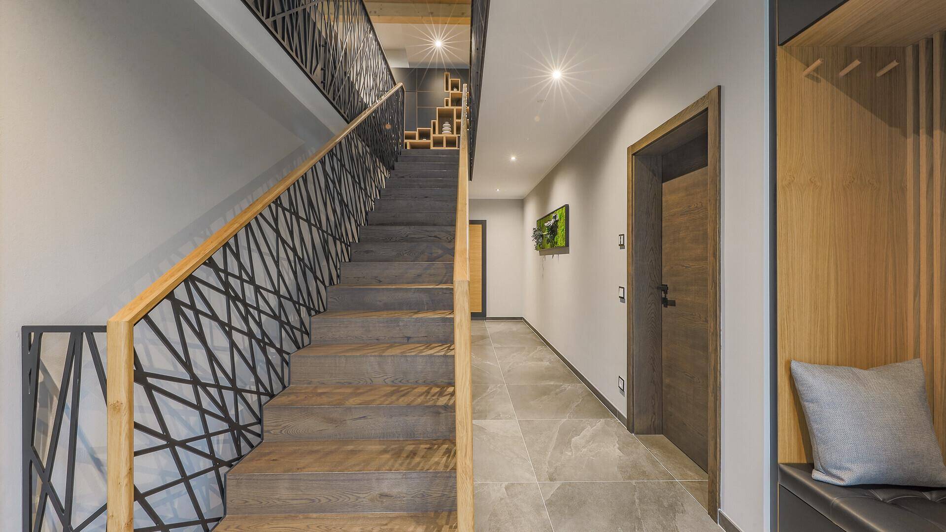 Heller Flur mit moderner Treppe, Holzdetails und Fliesenboden.
