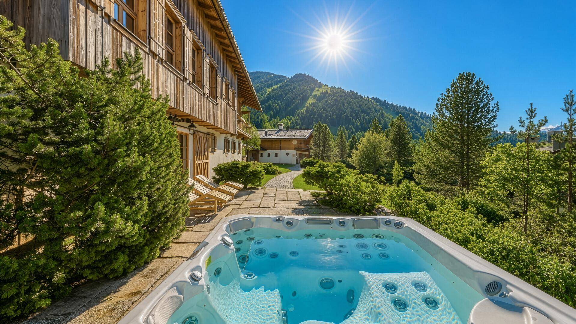Sonniger Außenbereich mit Whirlpool und Blick auf die umliegende Berglandschaft.