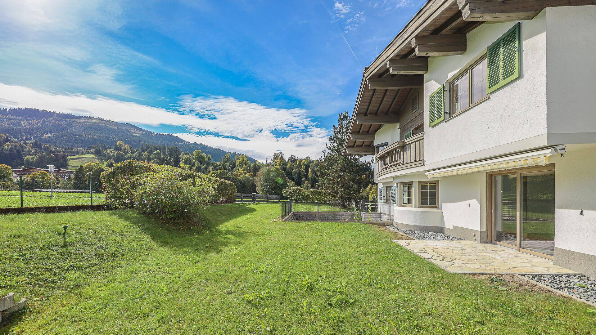 Großer grüner Gartenbereich mit Terrasse und weitem Blick auf die umliegende Hügellandschaft.