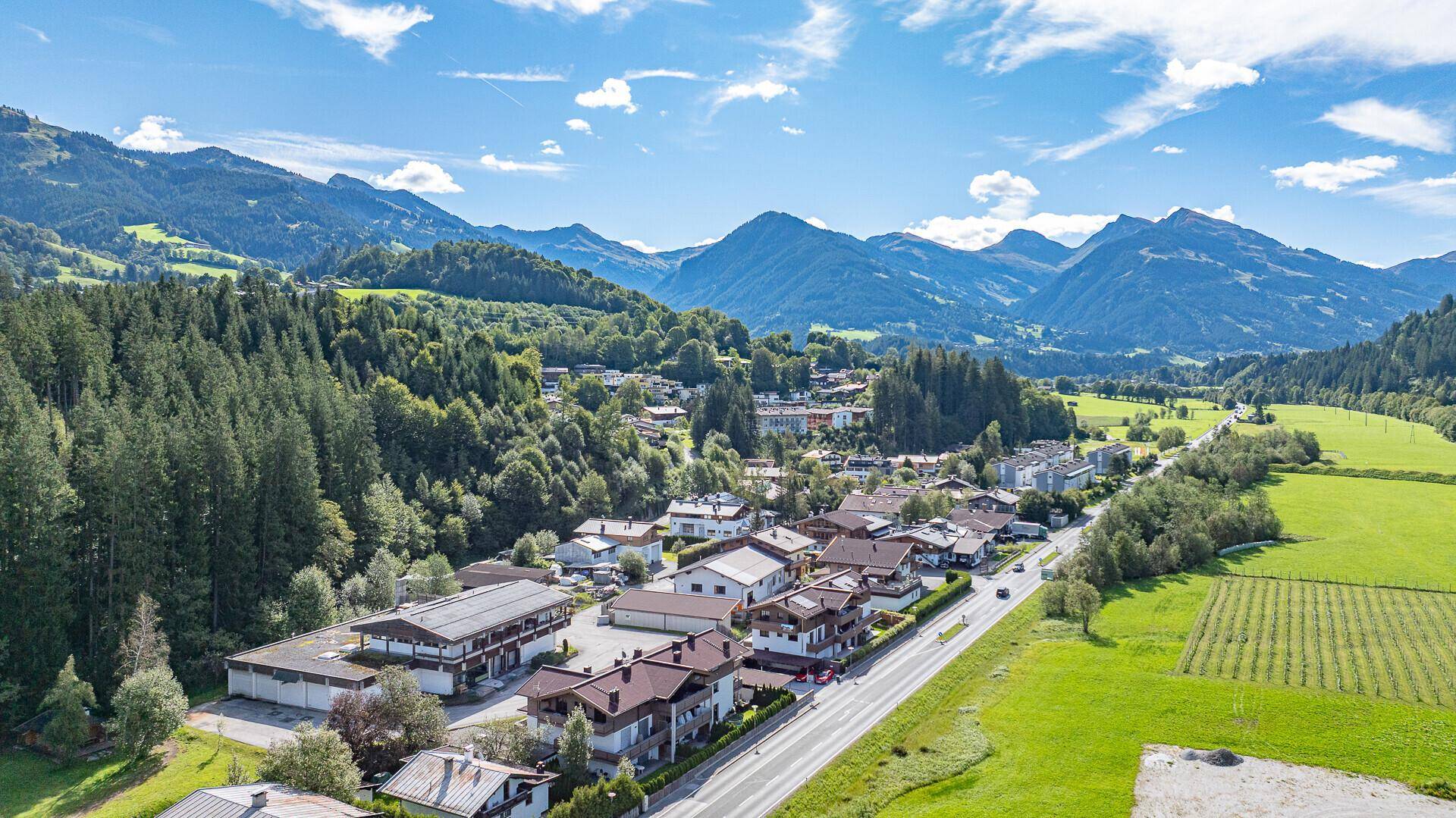 Luftaufnahme des Anwesens in einer malerischen Berglandschaft mit Wald und angrenzender Straße.