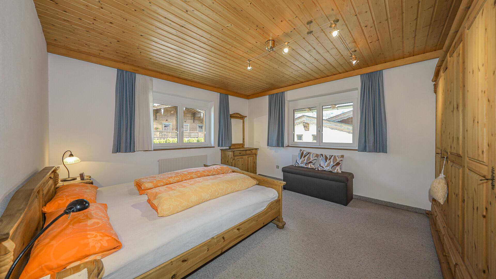 Gemütliches Schlafzimmer mit Holzbalkendecke, Teppichboden und traditionellen Möbeln.